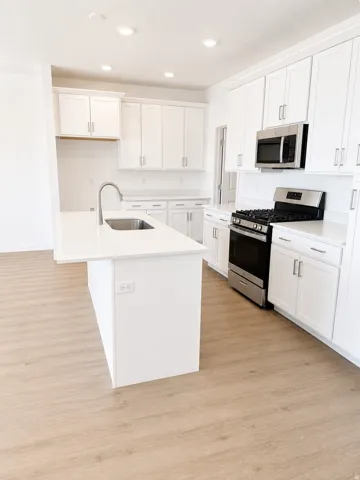 Modern kitchen featuring an expansive center island with an integrated sink and gooseneck faucet