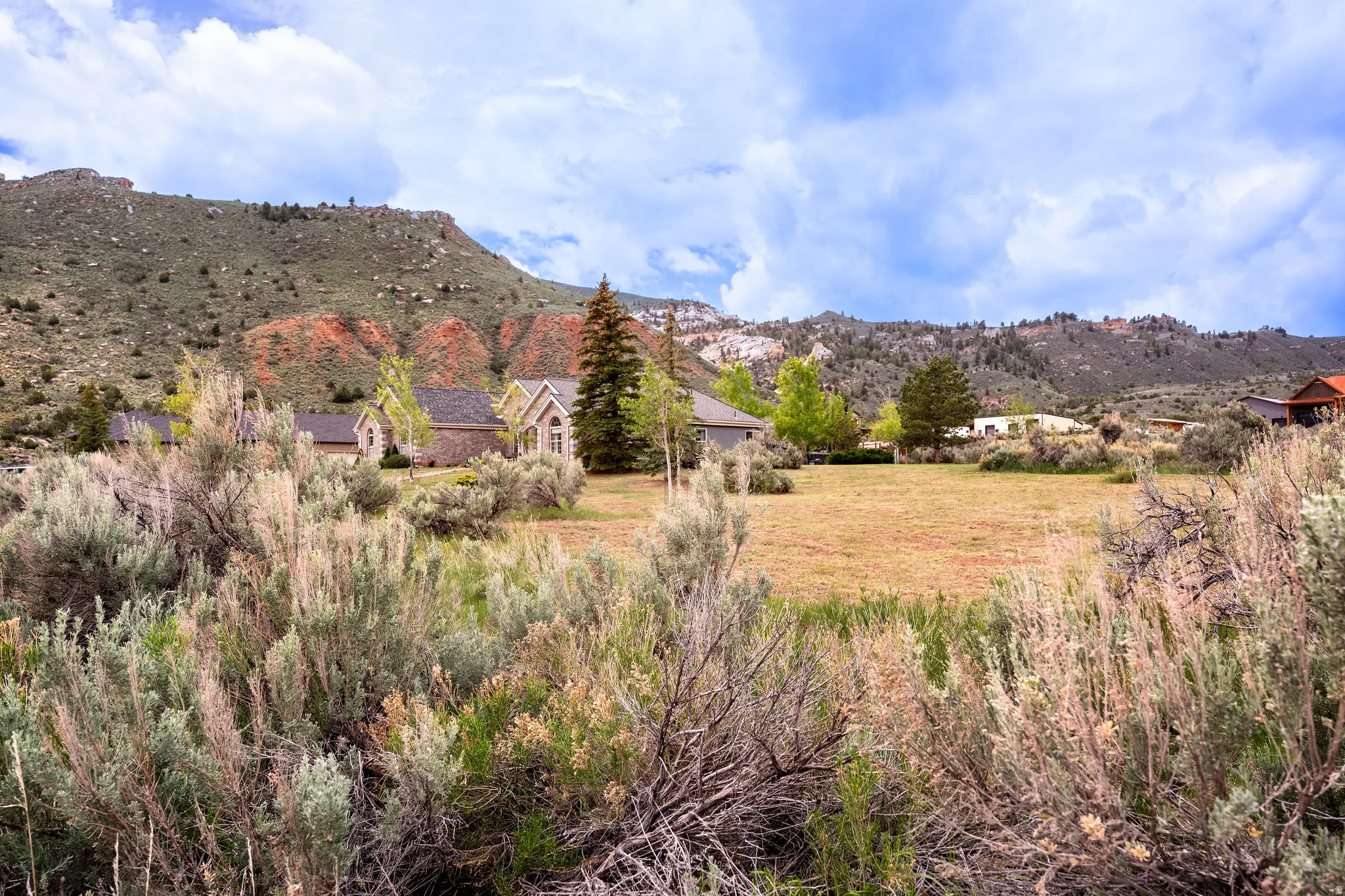 Expansive property with a large, level lawn area backed by a natural hillside