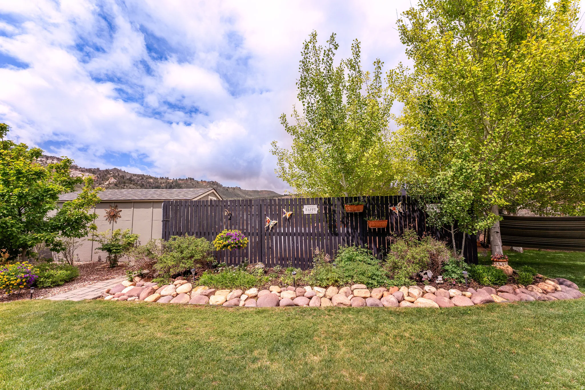 Expansive backyard with a manicured lawn, a privacy fence, and mature trees providing shade