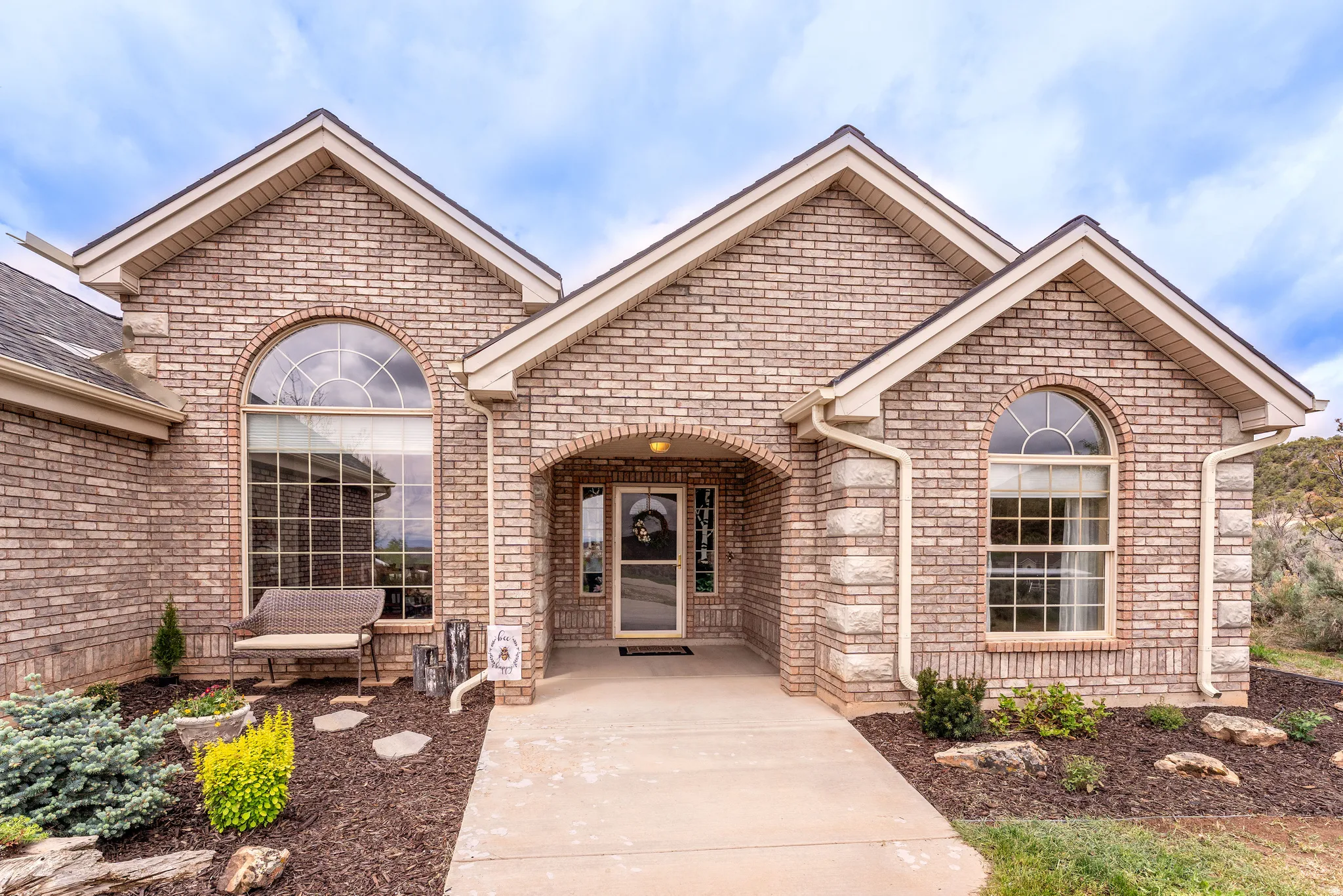Brick exterior featuring gabled rooflines, arched entry, and complementary stone accents