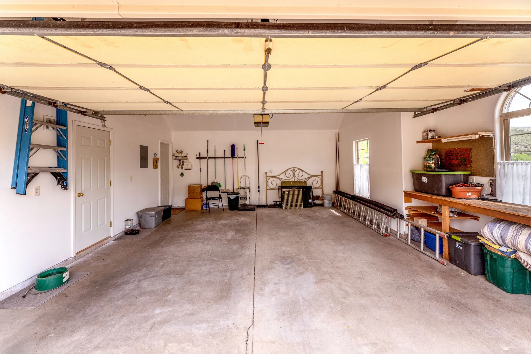 Spacious garage featuring a concrete floor, white interior walls, and a work bench