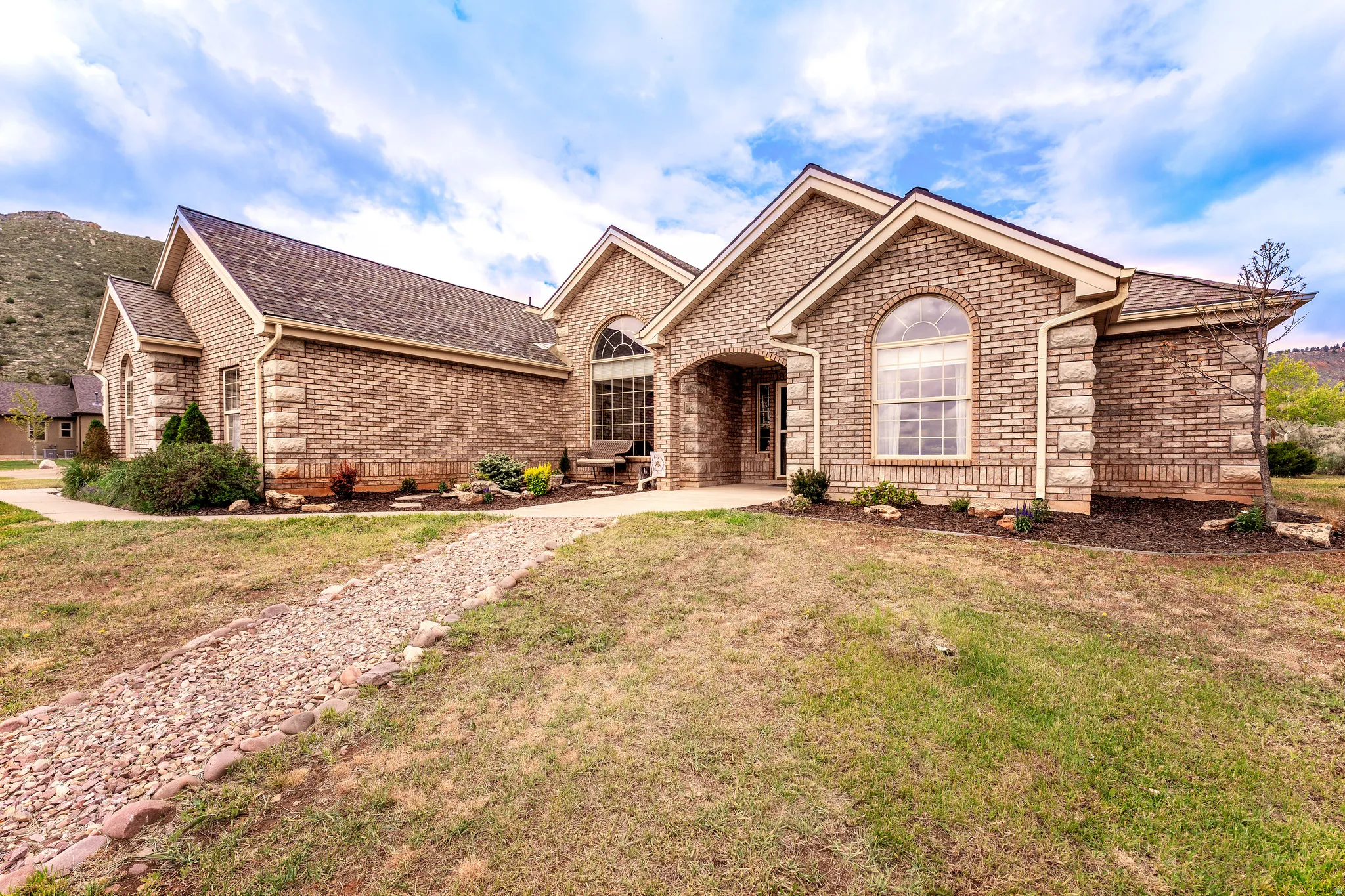 Brick and stone facade residence featuring arched windows and a covered entry