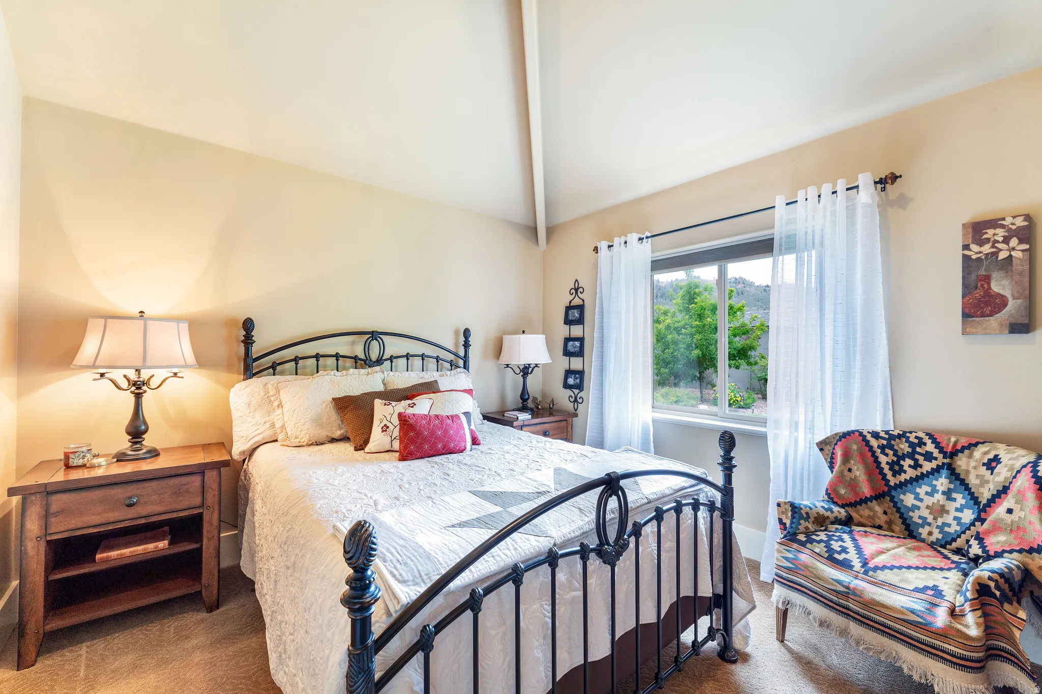Vaulted ceiling bedroom with a prominent window, and carpet flooring
