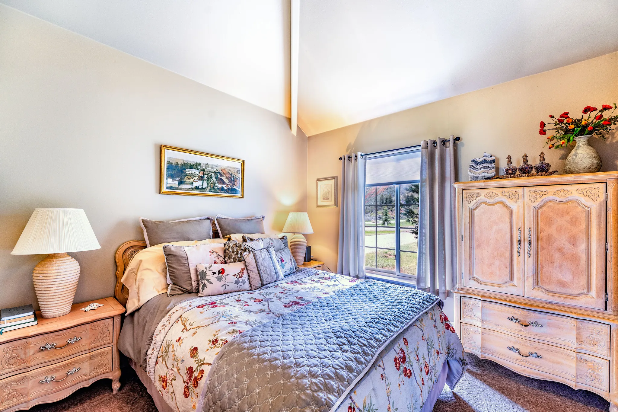 Vaulted ceiling bedroom with a large window, land carpet flooring