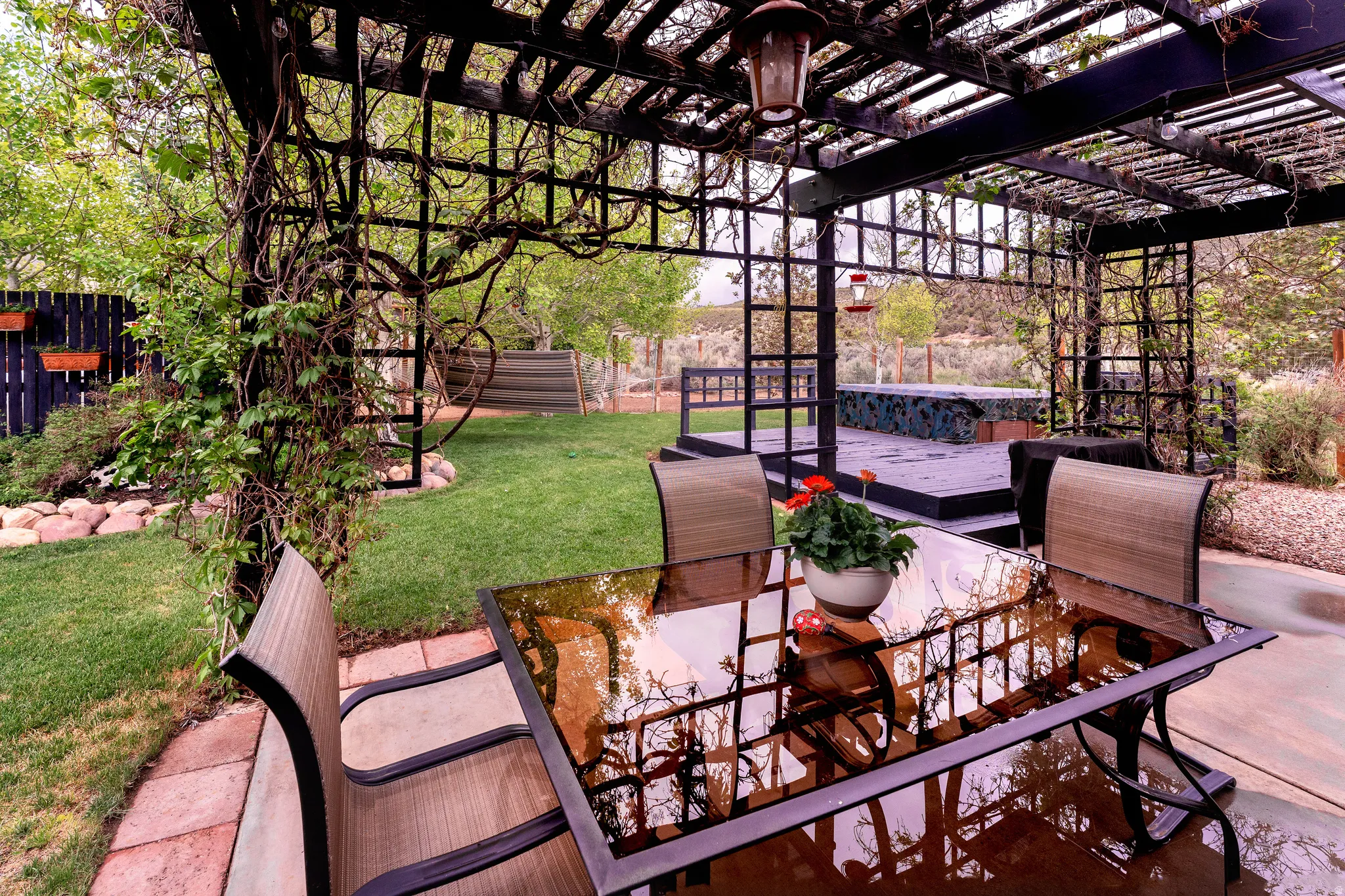 Covered concrete patio featuring a lattice pergola with established climbing vines