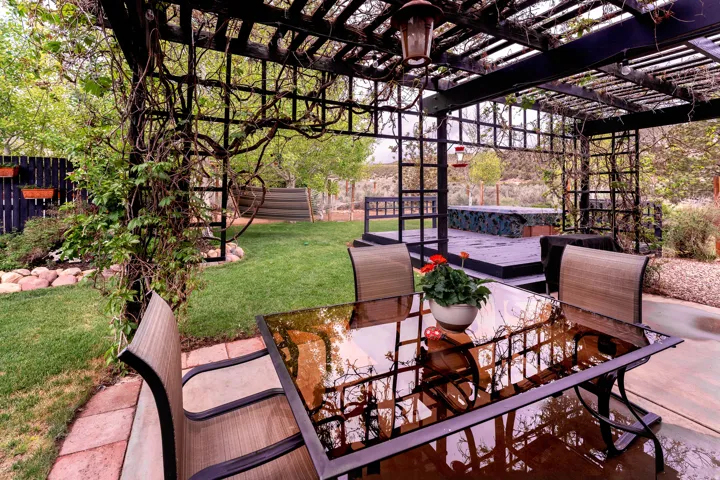 Covered concrete patio featuring a lattice pergola with established climbing vines