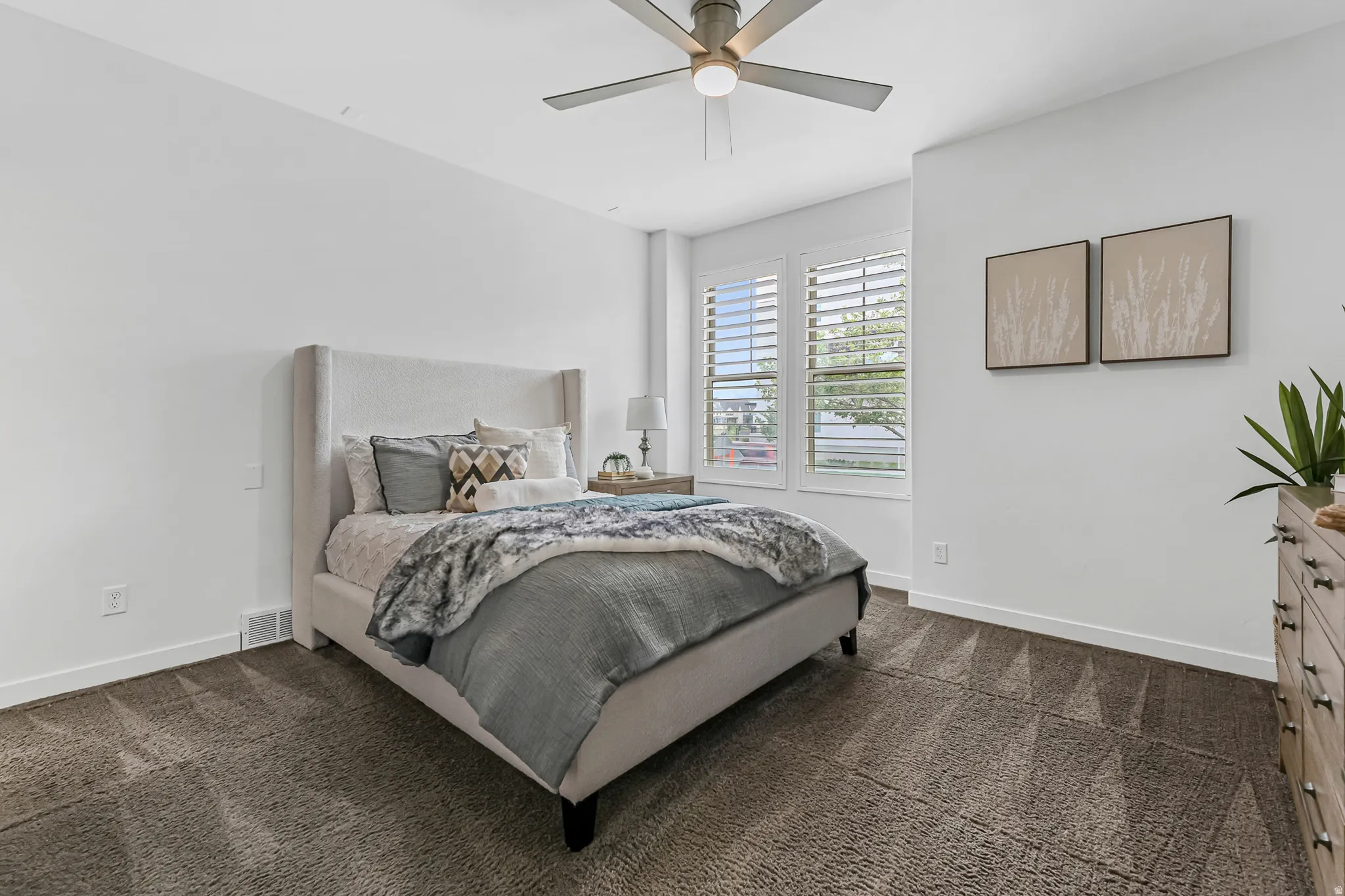 Primary bedroom with white walls and dark carpet flooring