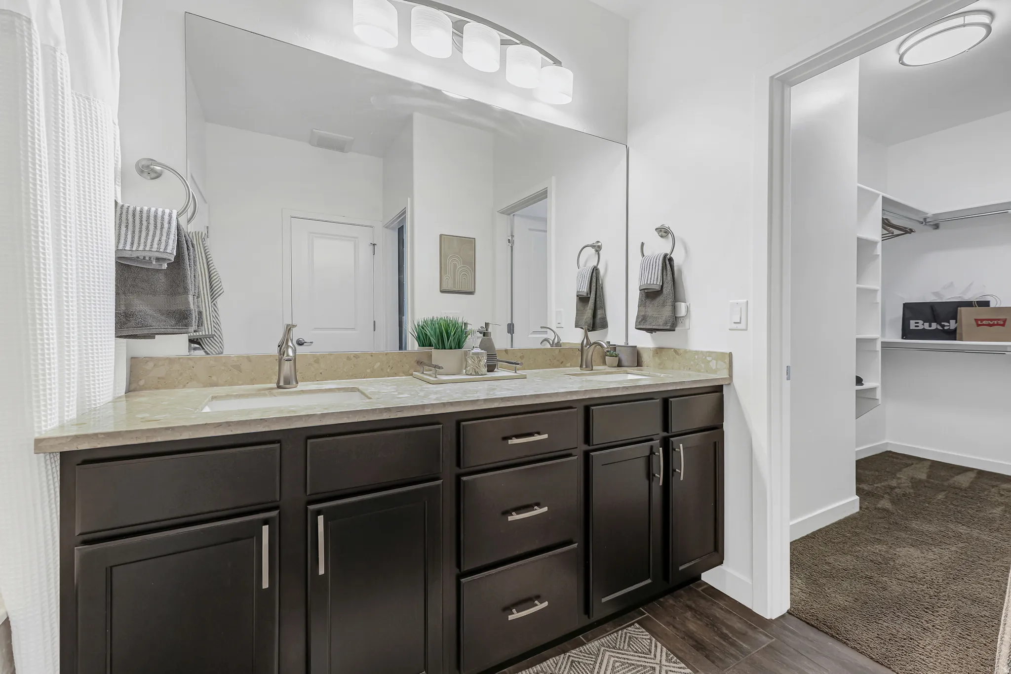 Primary bathroom featuring a dual vanity with dark wood cabinetry, light stone countertop, and two undermount sinks