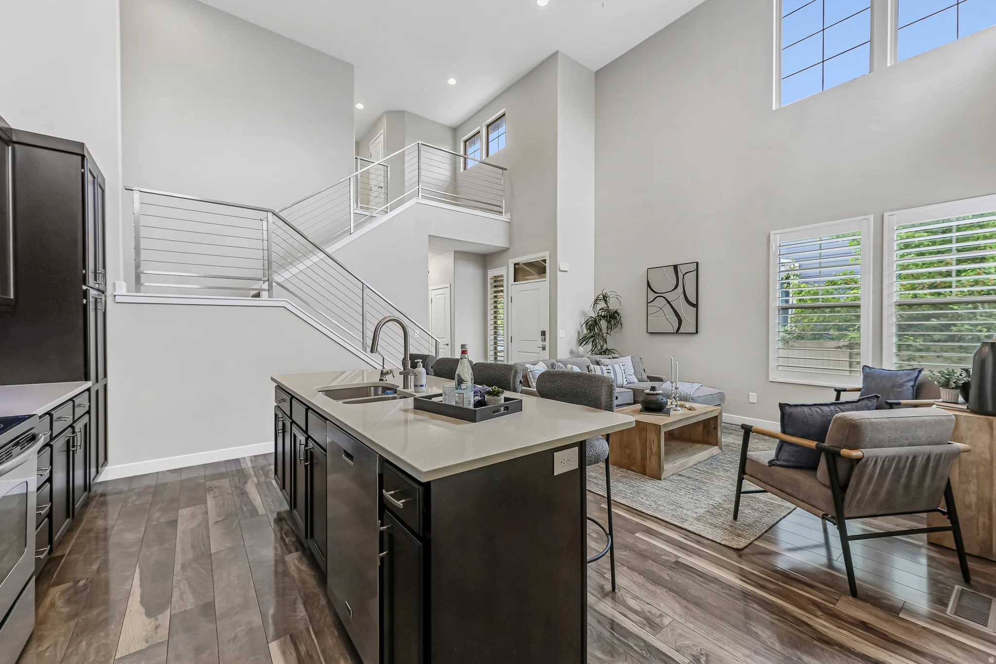 Kitchen island with an undermount sink and a light-toned countertop, dark wood-finish flooring, and a stainless steel appliance