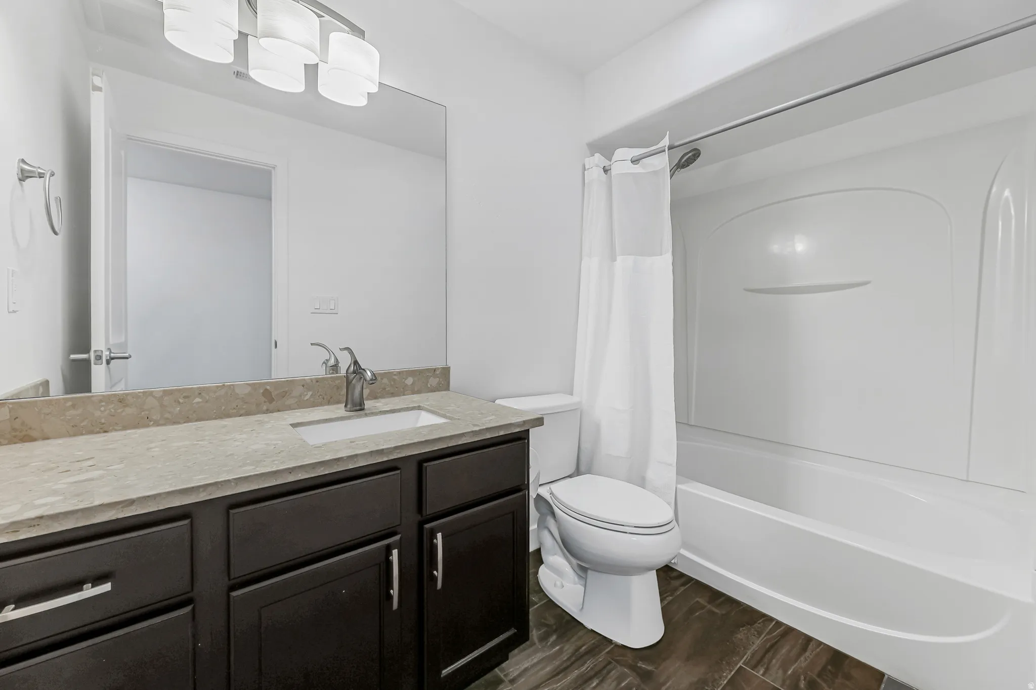 Bathroom featuring a dark wood-finish vanity with a light countertop, a built-in rectangular sink, and a chrome faucet
