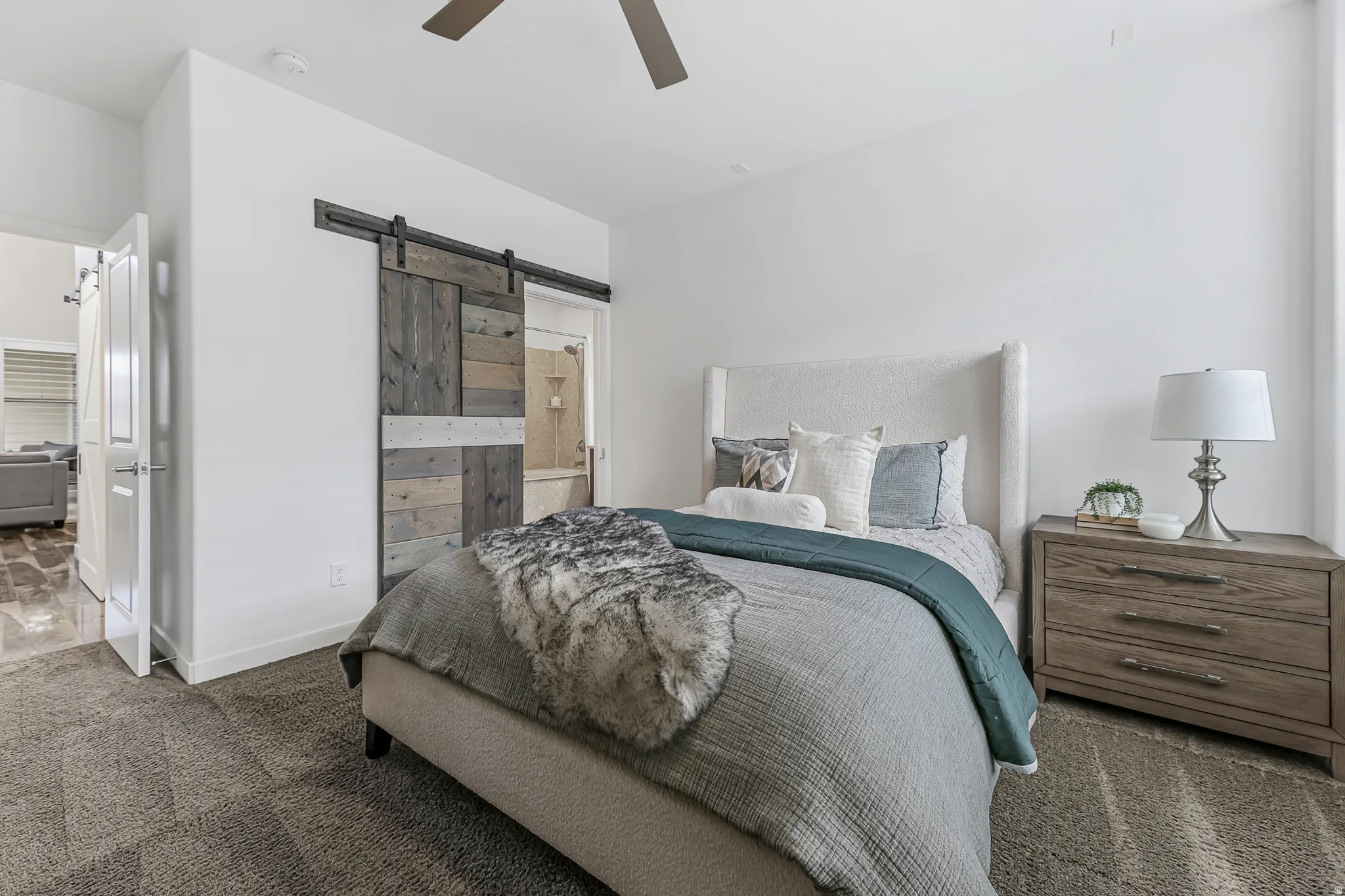 Spacious primary bedroom featuring a rustic barn door, recessed lighting, and a ceiling fan