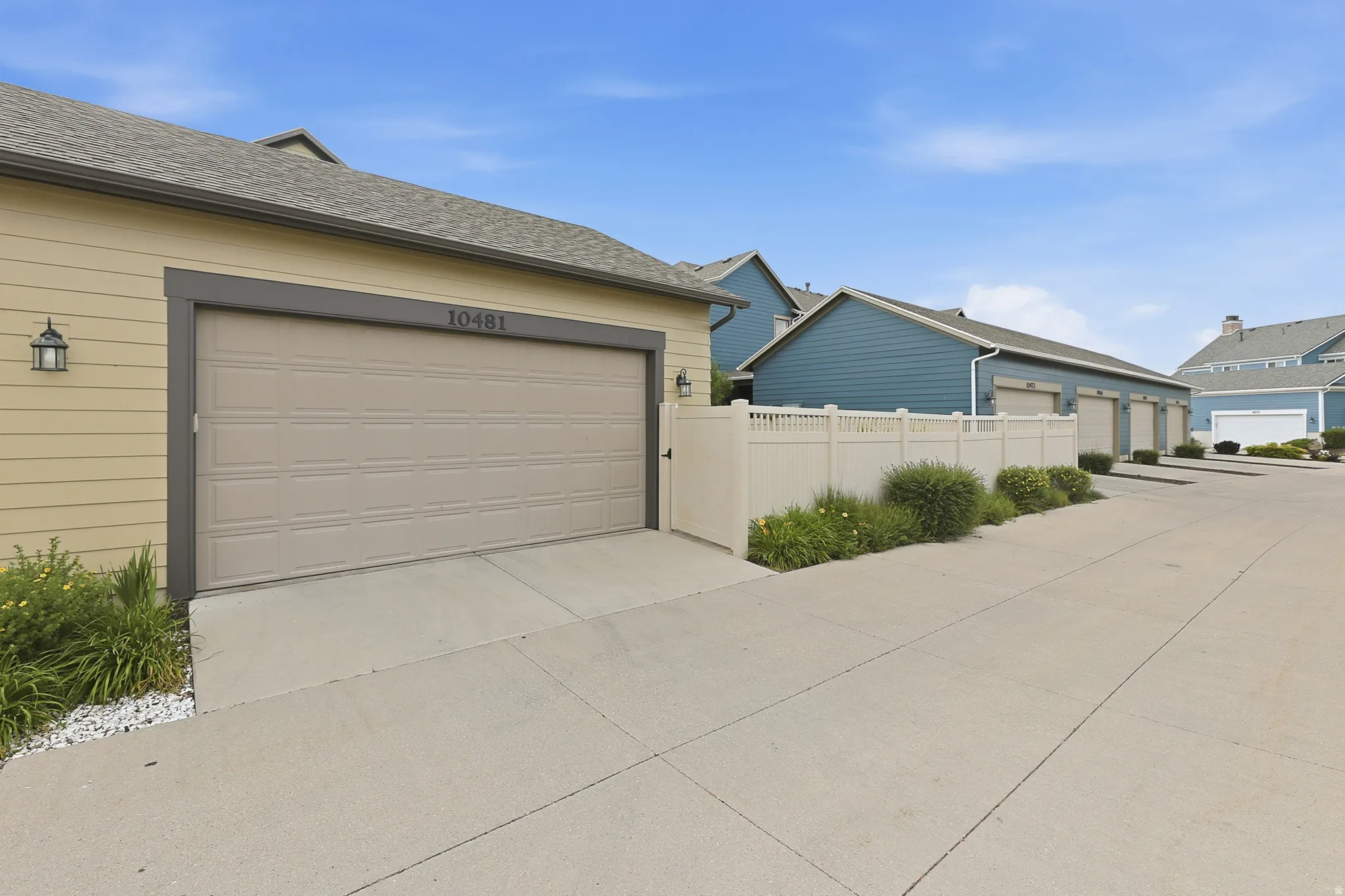Attached garage with a panel door, featuring a dedicated concrete driveway and exterior lighting fixture