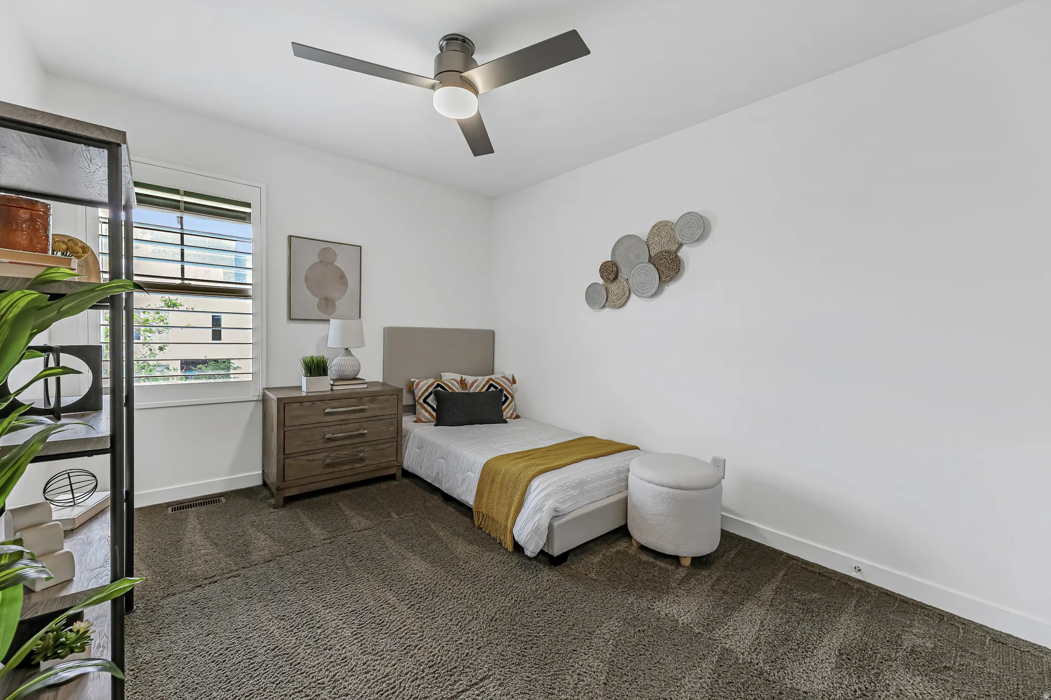 Bedroom with white walls complement dark gray carpeting and a modern ceiling fan with integrated lighting