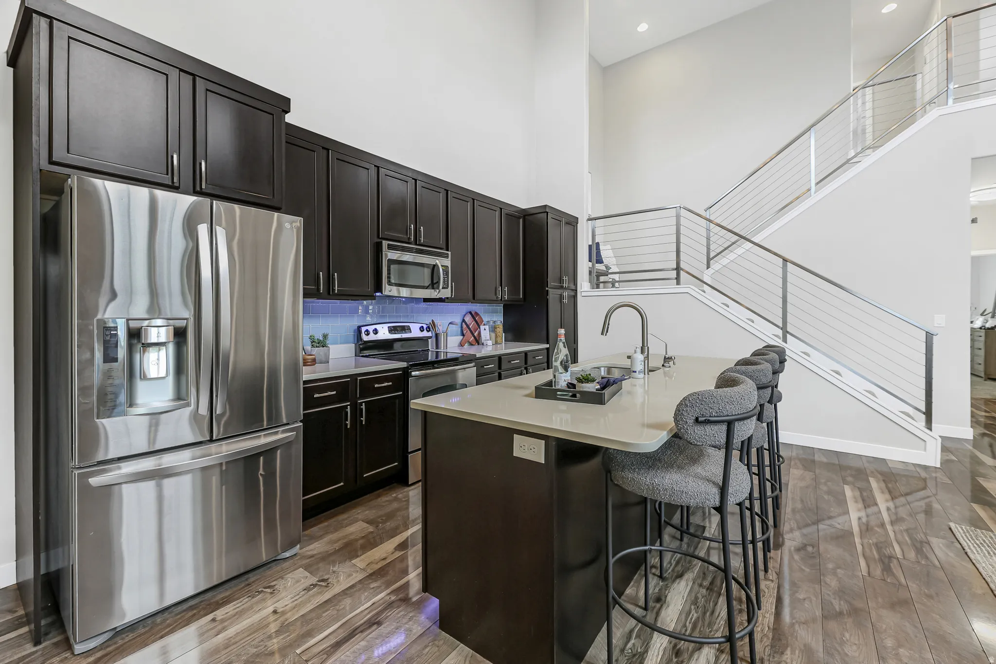 Kitchen featuring dark cabinetry, stainless steel appliances, and a light-toned island with a built-in sink