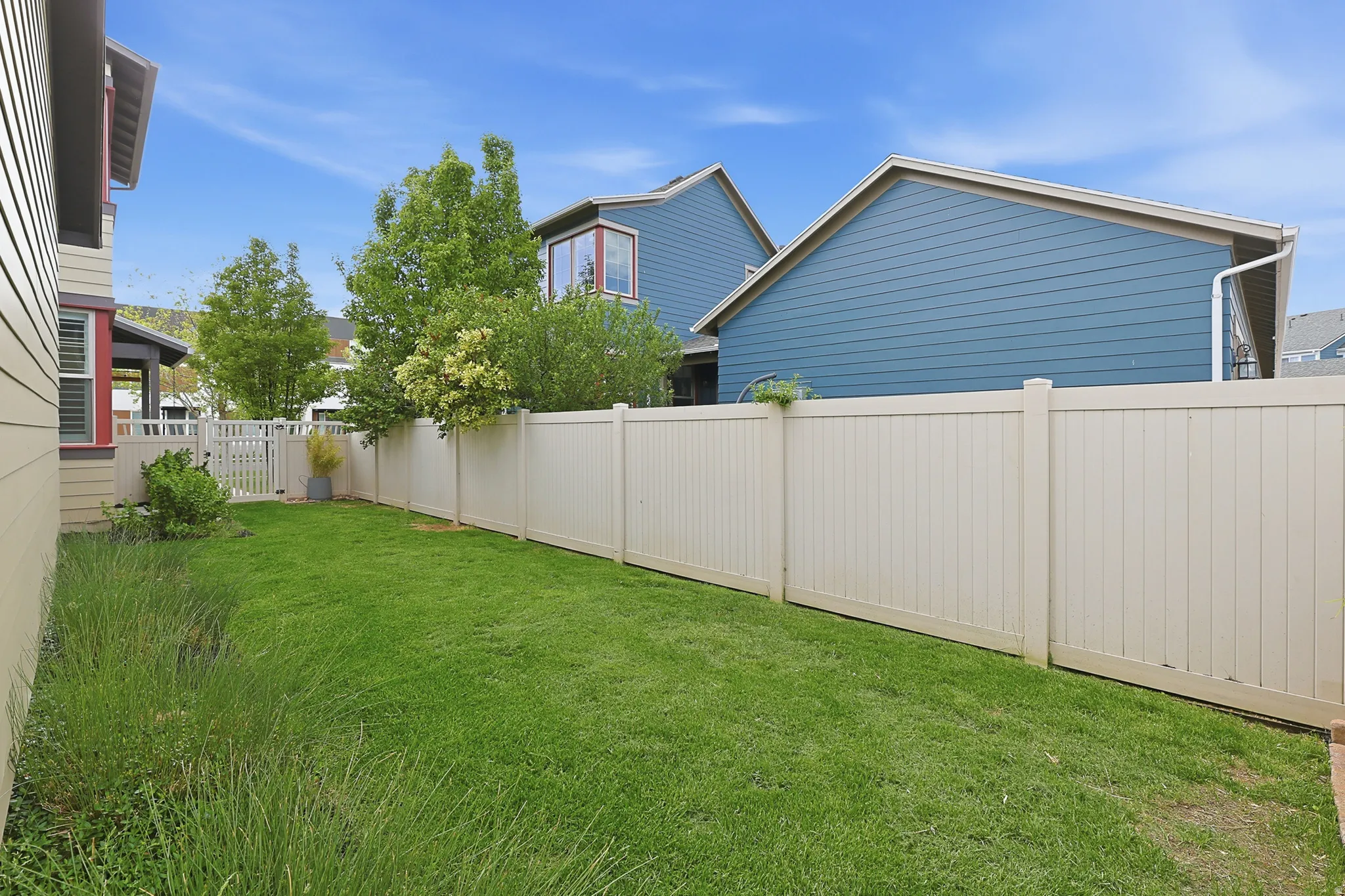 Expansive green lawn area featuring a full-height privacy fence