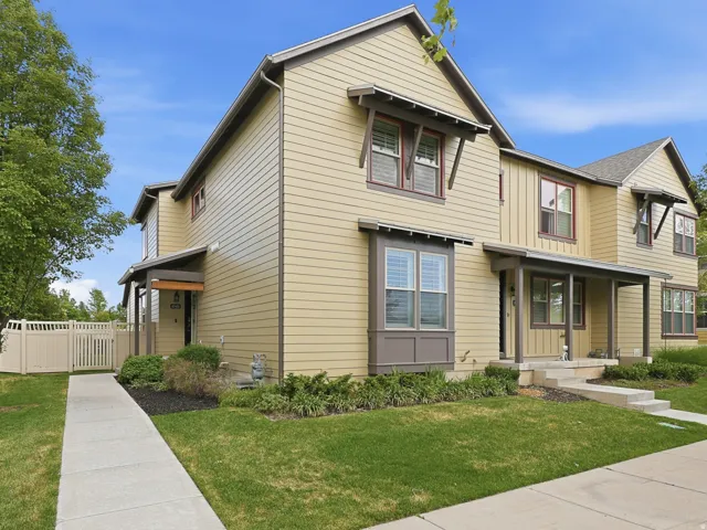 Contemporary townhome exterior with horizontal siding, covered entry porch, bay window feature, window awnings, and a concrete pathway leading to the entrance