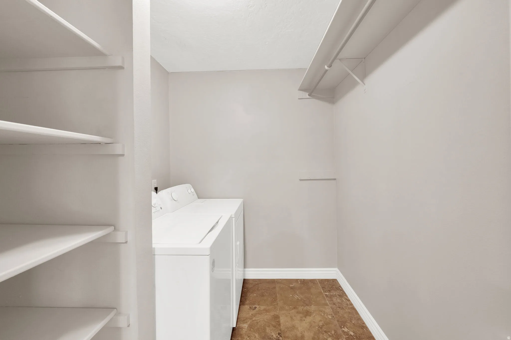 Dedicated laundry space featuring a white top-load washer and dryer set