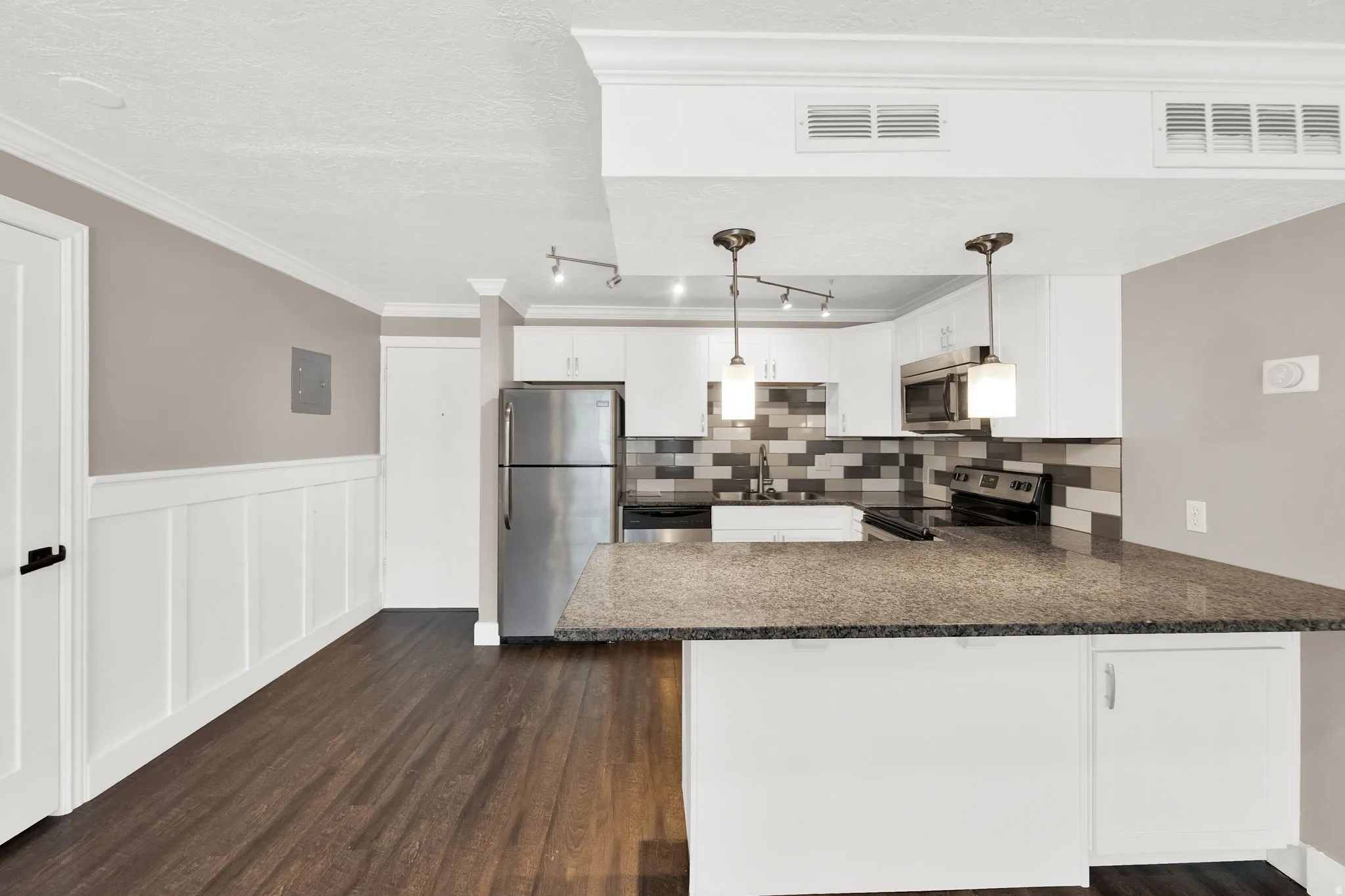 Kitchen featuring granite countertops, stainless steel appliances, and a mosaic tile backsplash