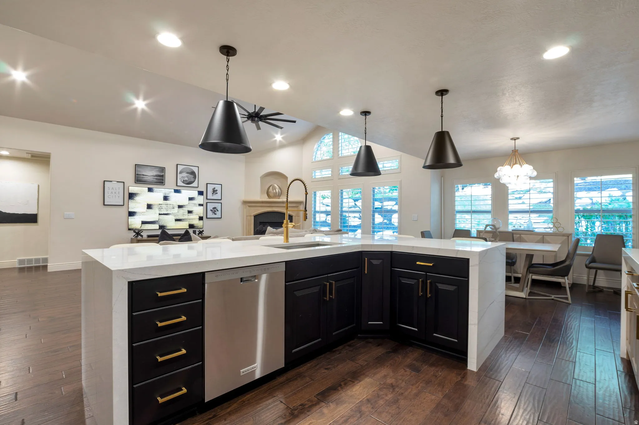 Modern kitchen island featuring dark cabinetry with gold-finish hardware, a stainless steel dishwasher, and a white countertop