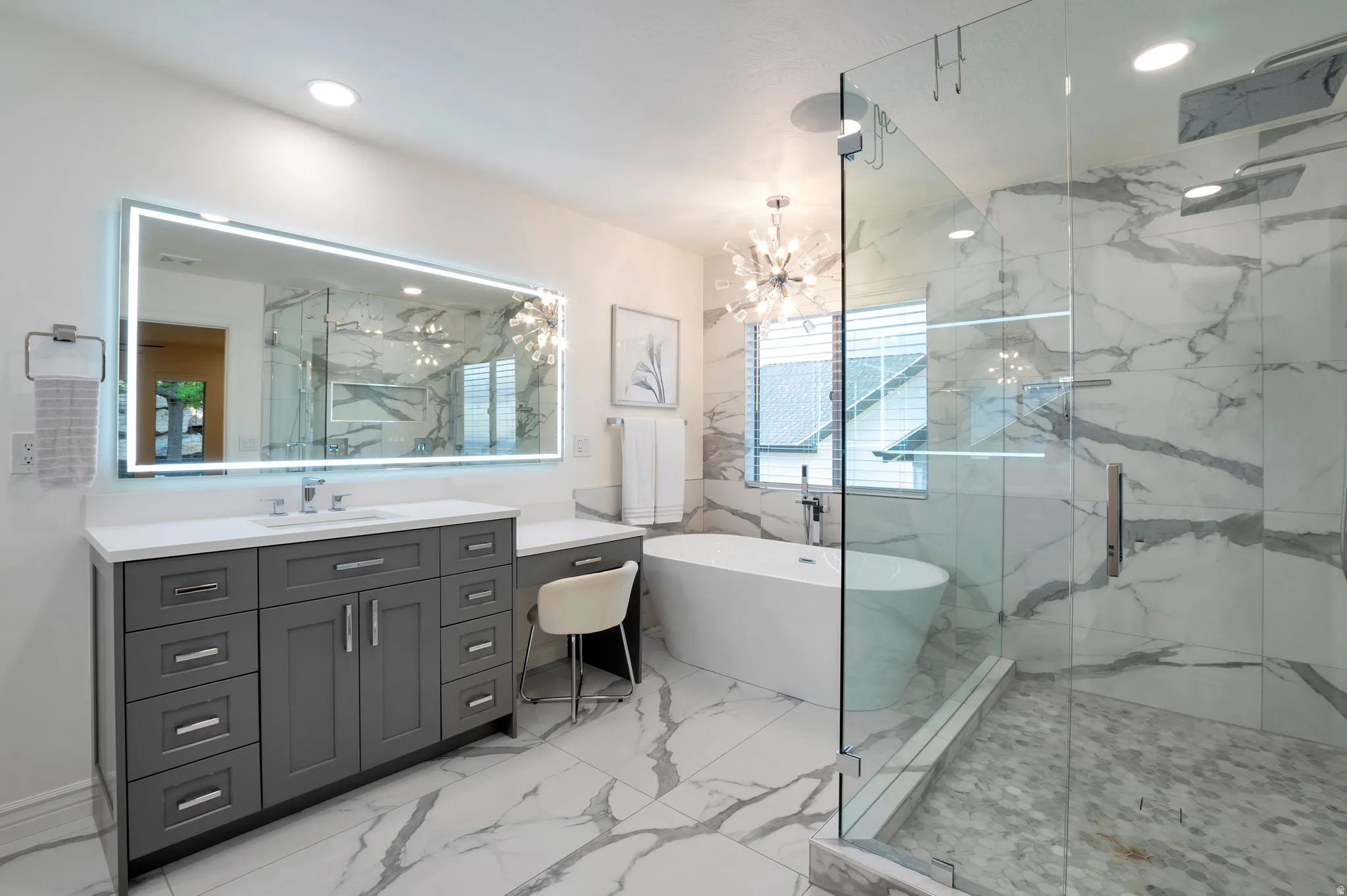 Contemporary bathroom featuring a freestanding soaking tub, a spacious glass-enclosed shower, a large vanity with integrated lighting, a quartz countertop, and large-format porcelain tile flooring