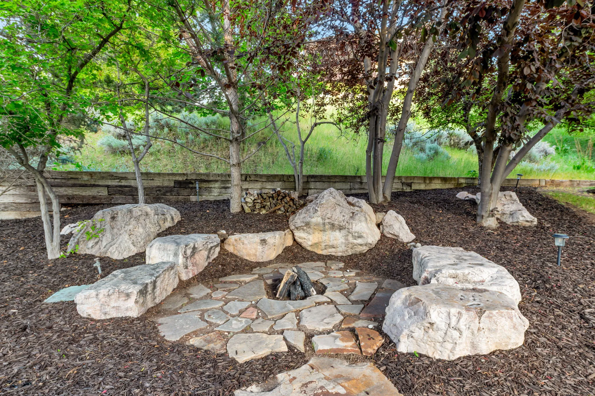 Outdoor fire pit area featuring a natural stone border and flagstone base