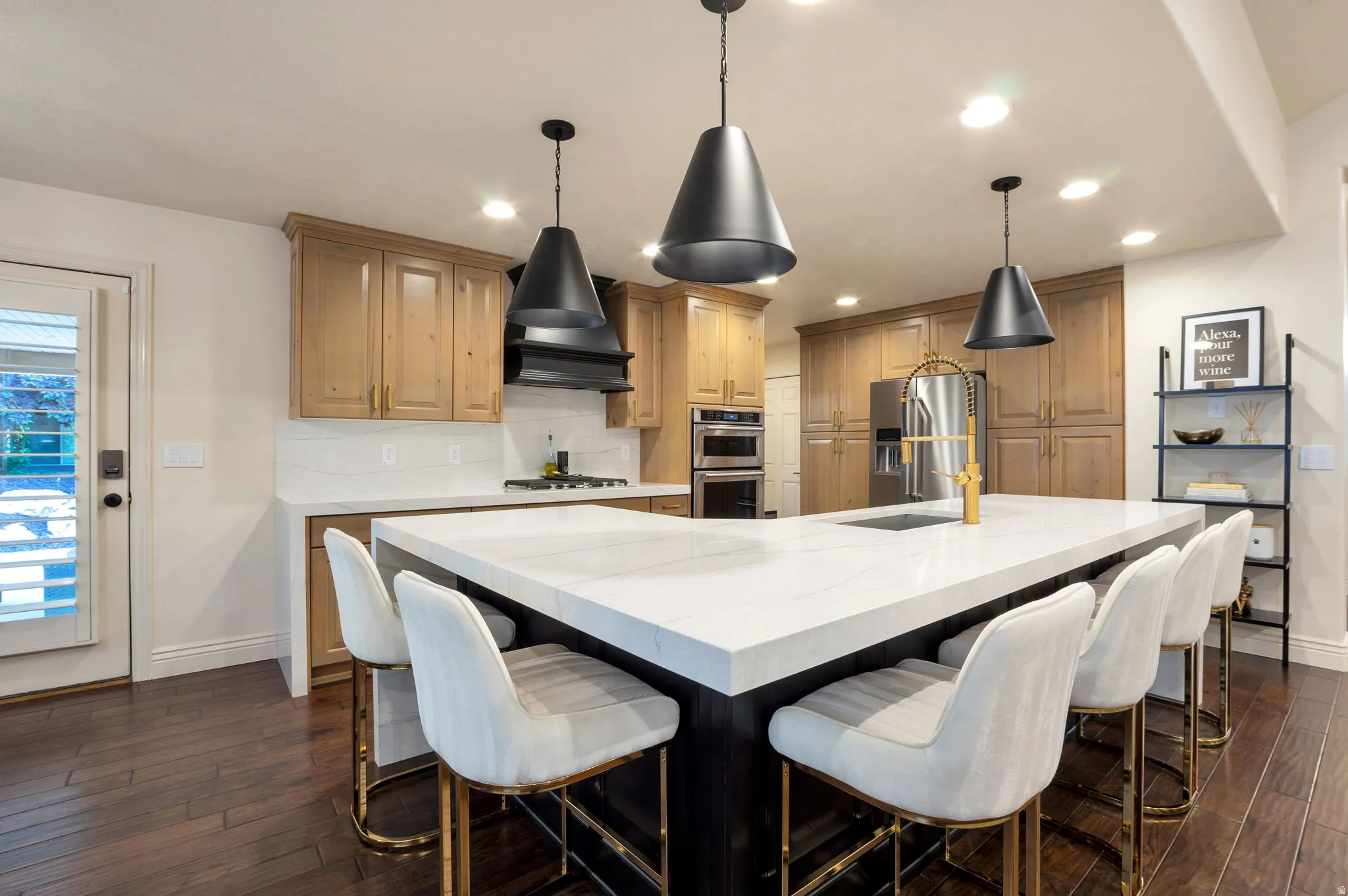 Gourmet kitchen featuring a large central island with seating, stone countertops, wood-finish flooring, recessed lighting, and a gold-tone faucet