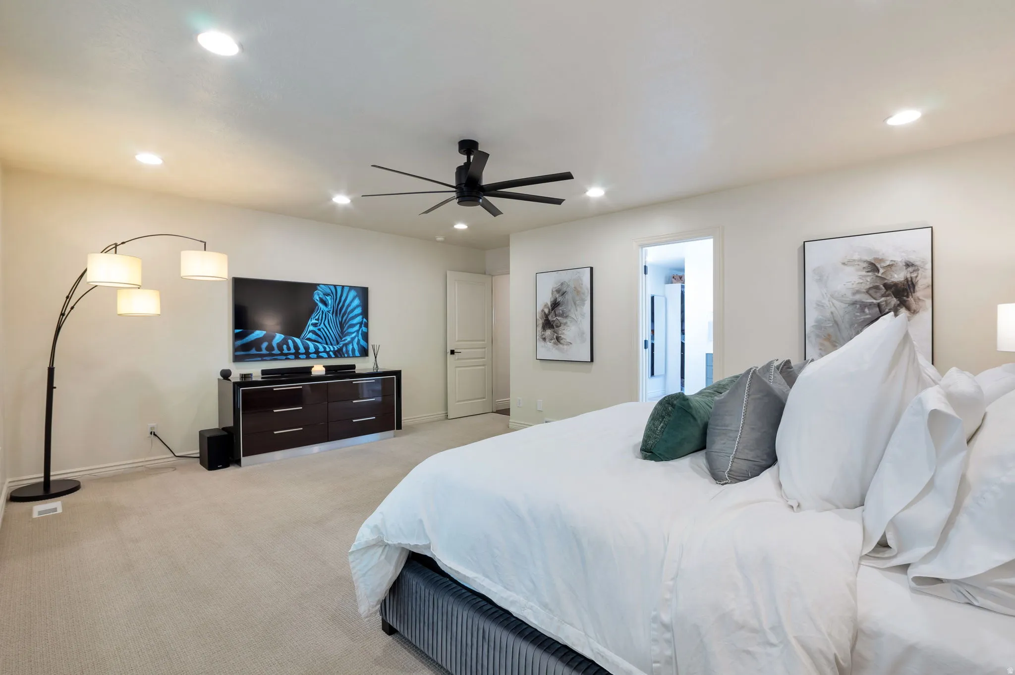 Spacious room featuring neutral-toned carpet flooring, recessed lighting, and a dark-bladed ceiling fan