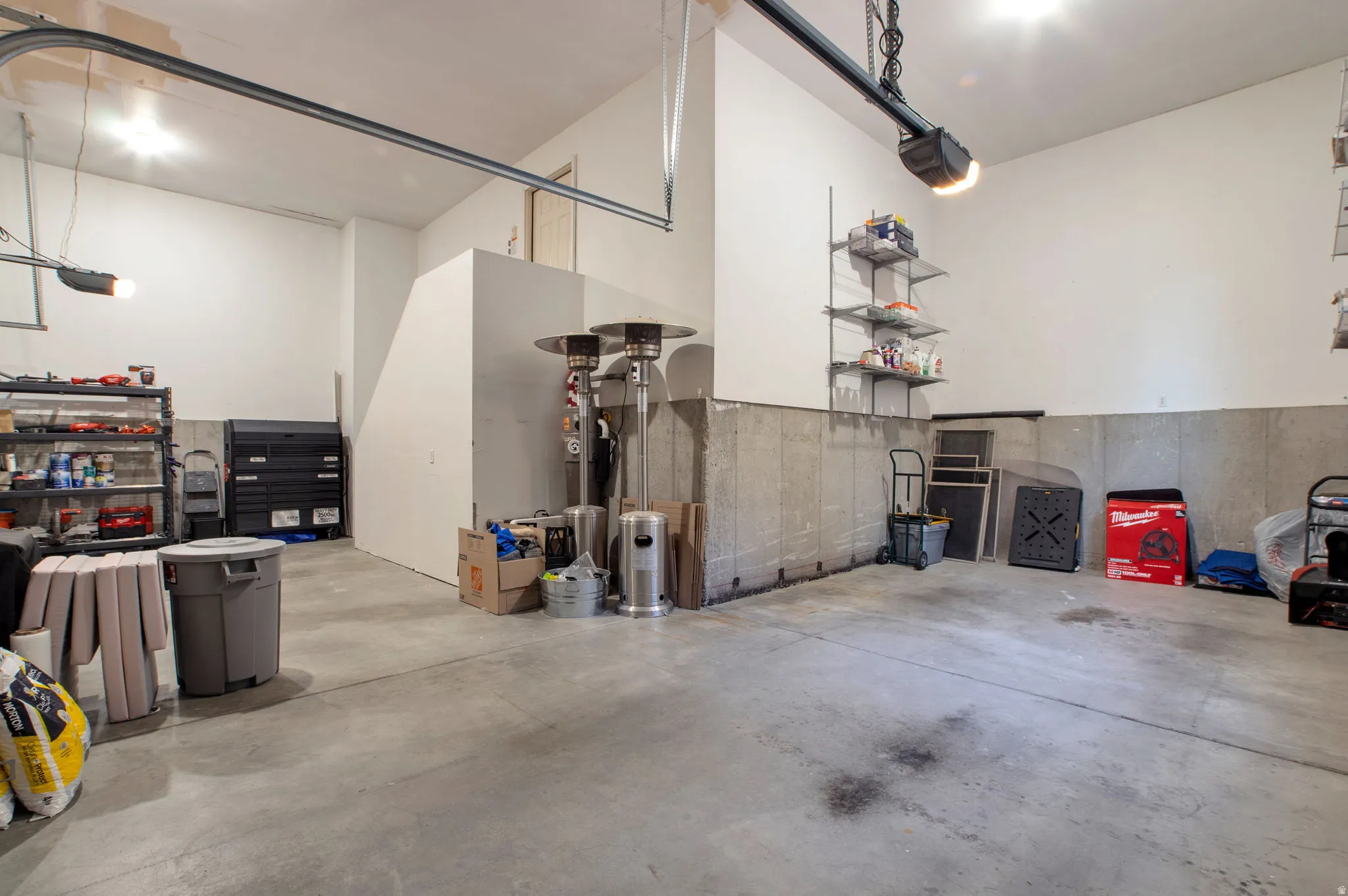 Spacious garage with concrete flooring, exposed concrete foundation walls, and bright overhead lighting