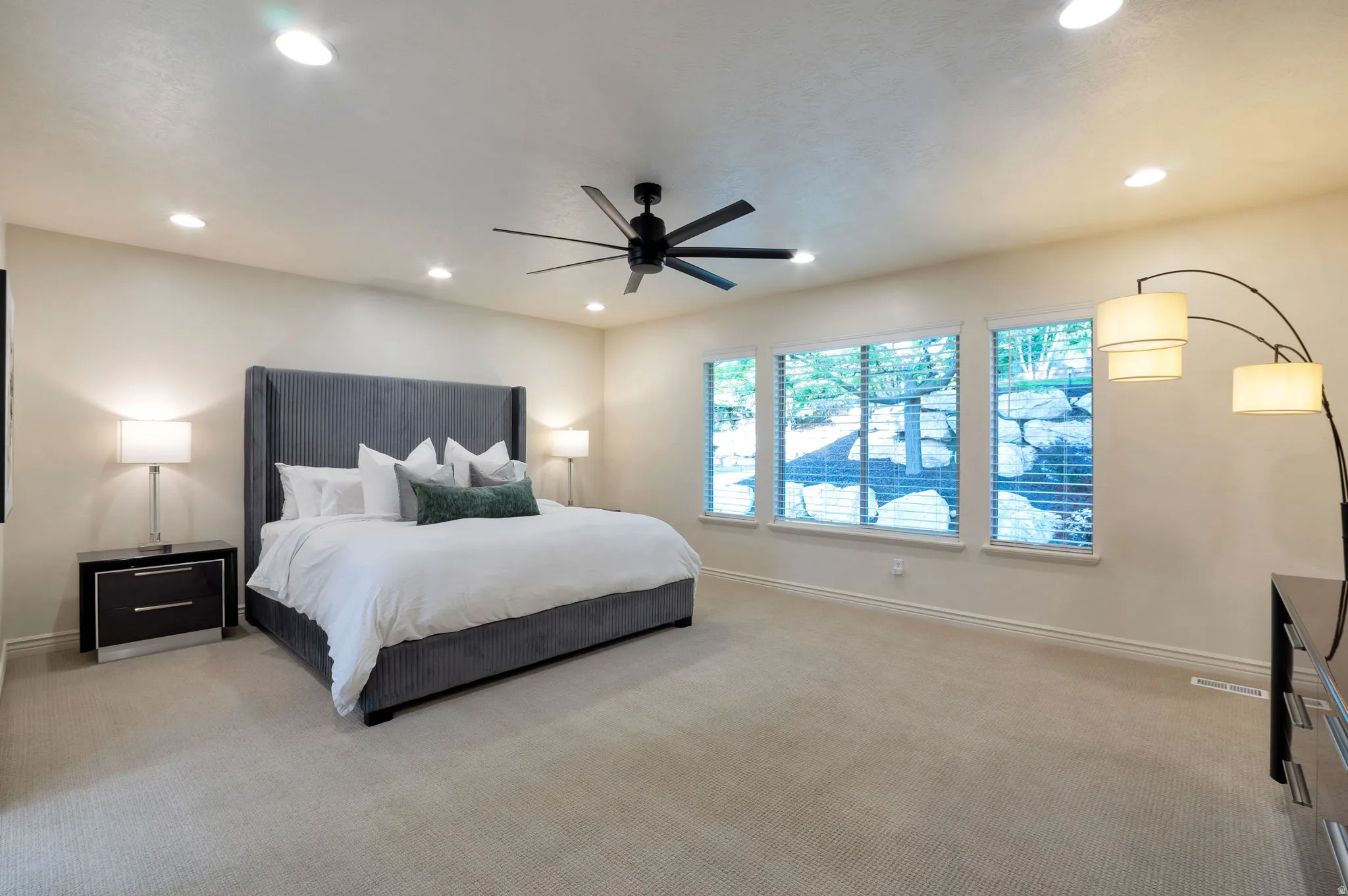 Spacious bedroom featuring light-toned carpeting, recessed lighting, and a contemporary ceiling fan