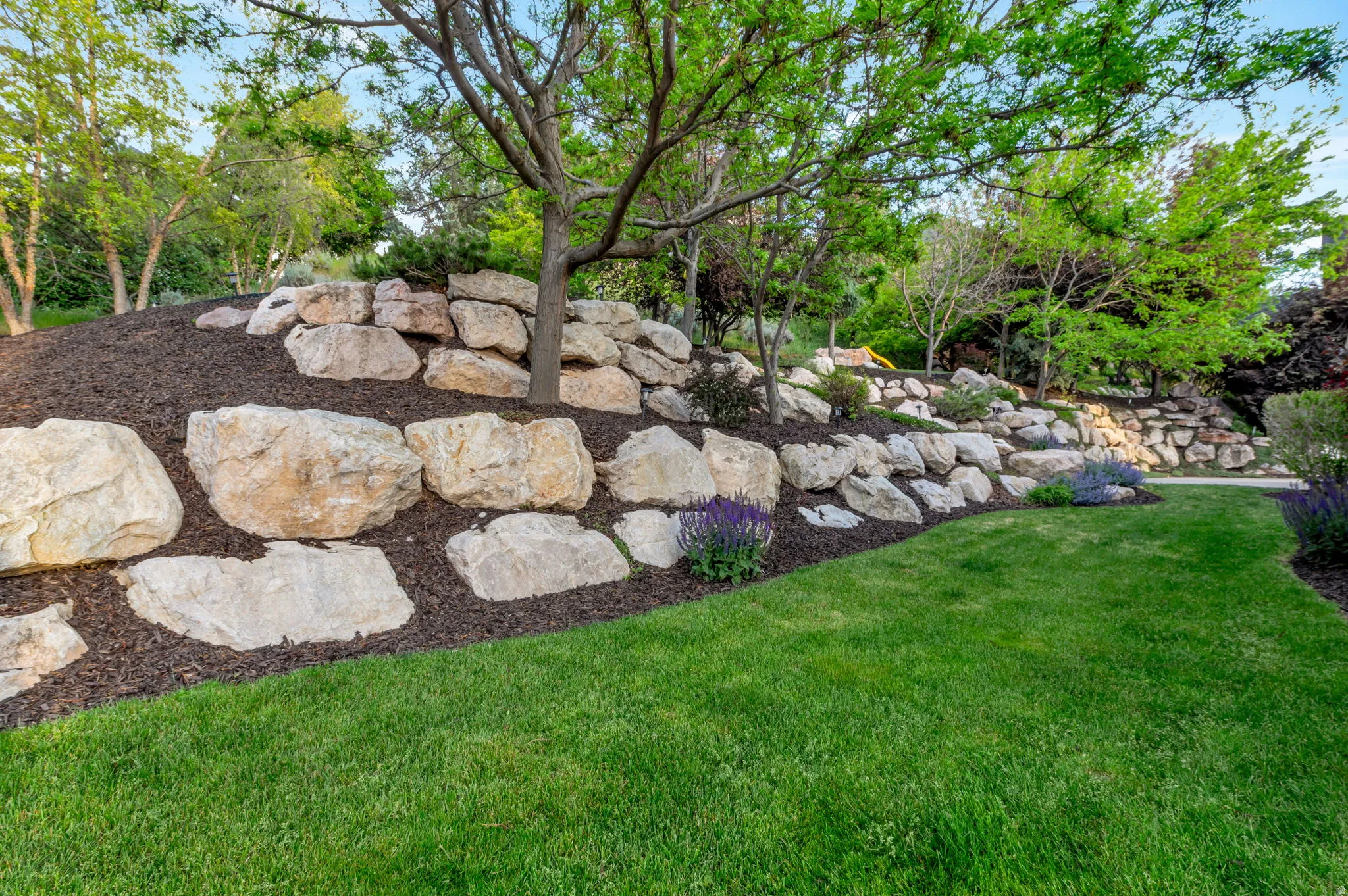 Lush green lawn bordered by a natural rock retaining wall