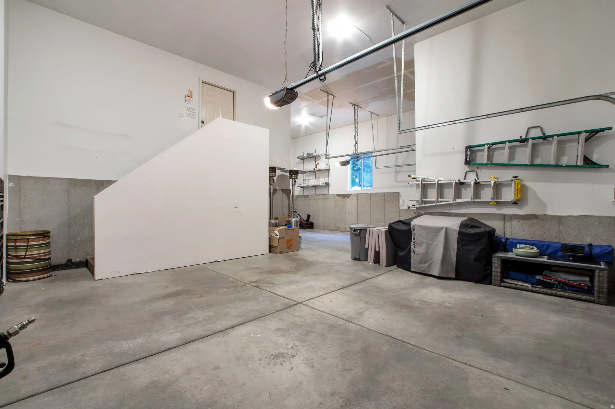 Spacious garage featuring a concrete floor, painted white walls, overhead lighting, and an overhead garage door opener