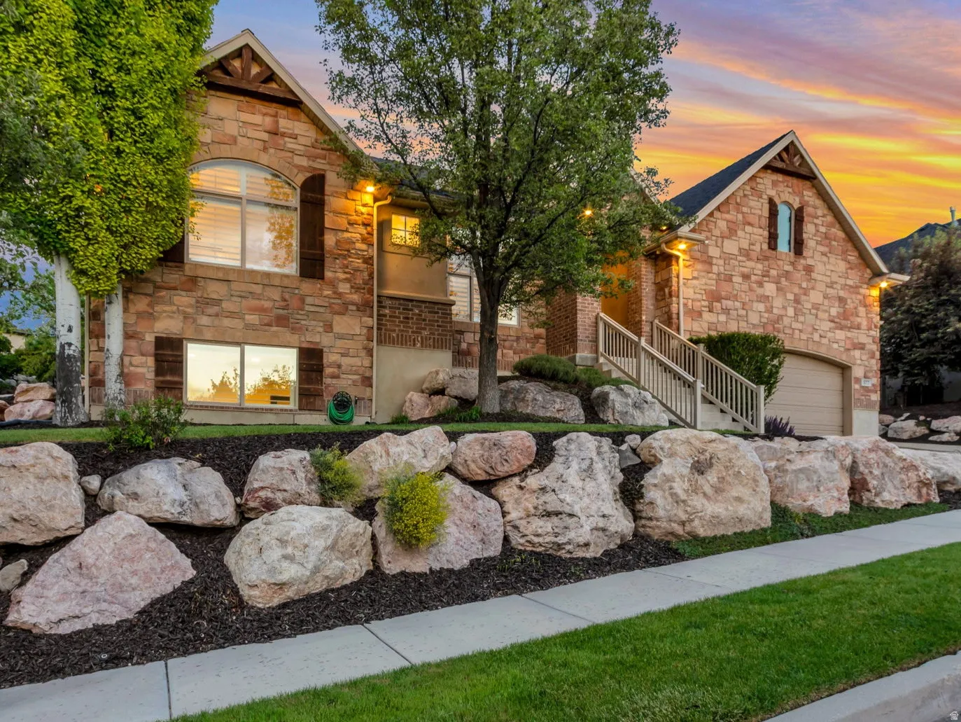 Stone-clad exterior featuring multiple gables, arched windows, and a two-car garage