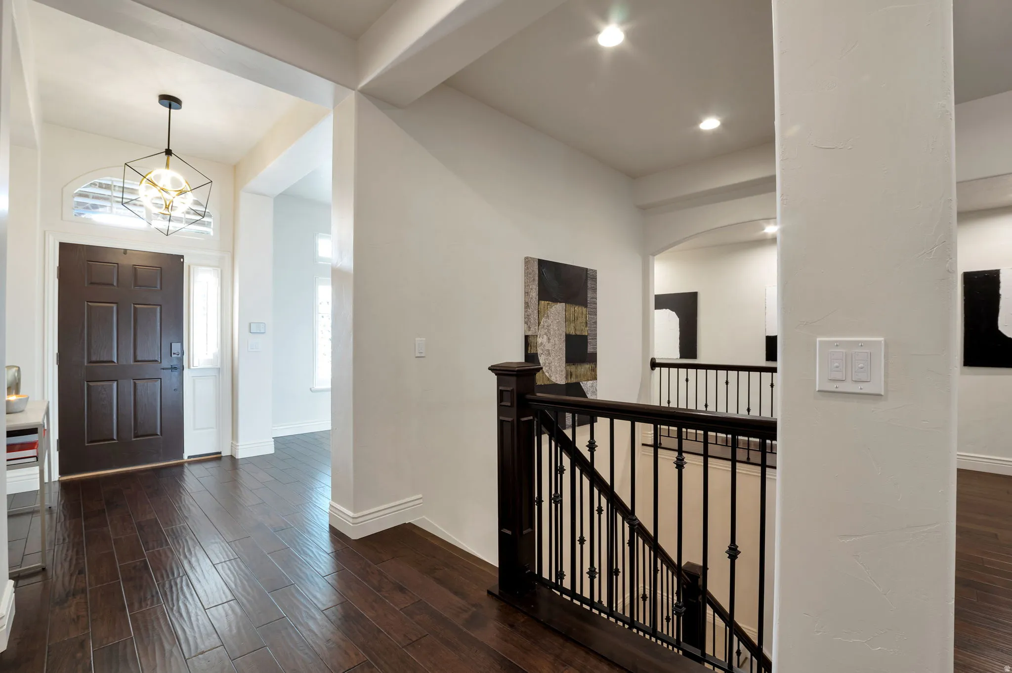 Entry foyer featuring dark wood-finish flooring, a paneled front door with side light and transom windows, and a contemporary geometric chandelier