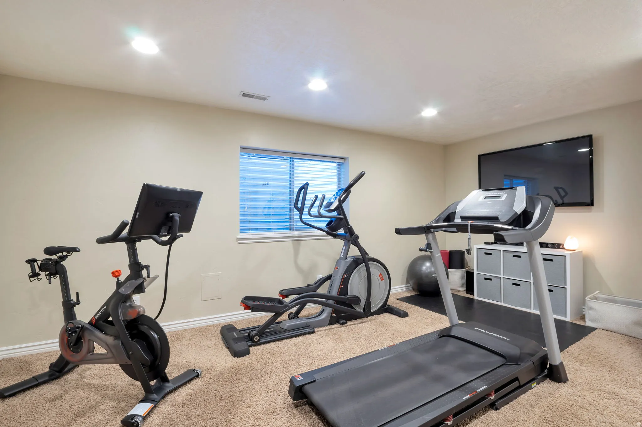 Carpeted room with recessed lighting and a single window featuring horizontal blinds