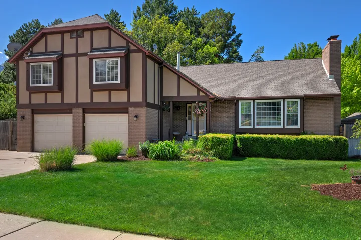Tudor-style exterior featuring a two-car garage, brick accents, and a prominent chimney