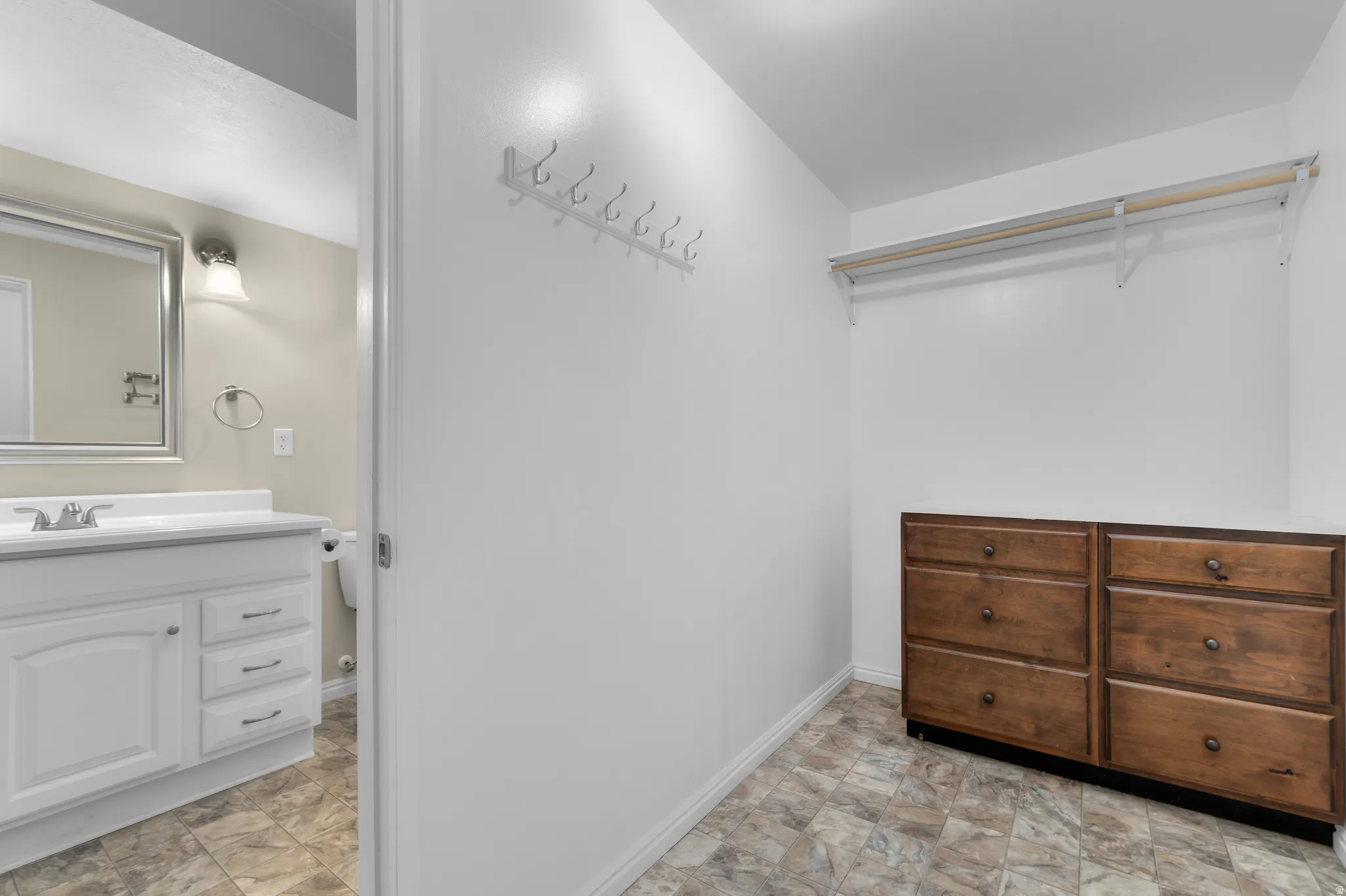 Walk-in closet featuring a built-in wooden dresser with six drawers, white wire shelving, and wall-mounted coat hooks