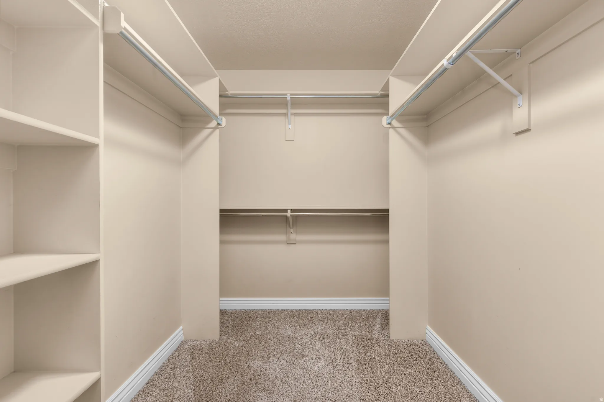 Walk-in closet with carpet flooring, built-in shelving, and multiple hanging rods
