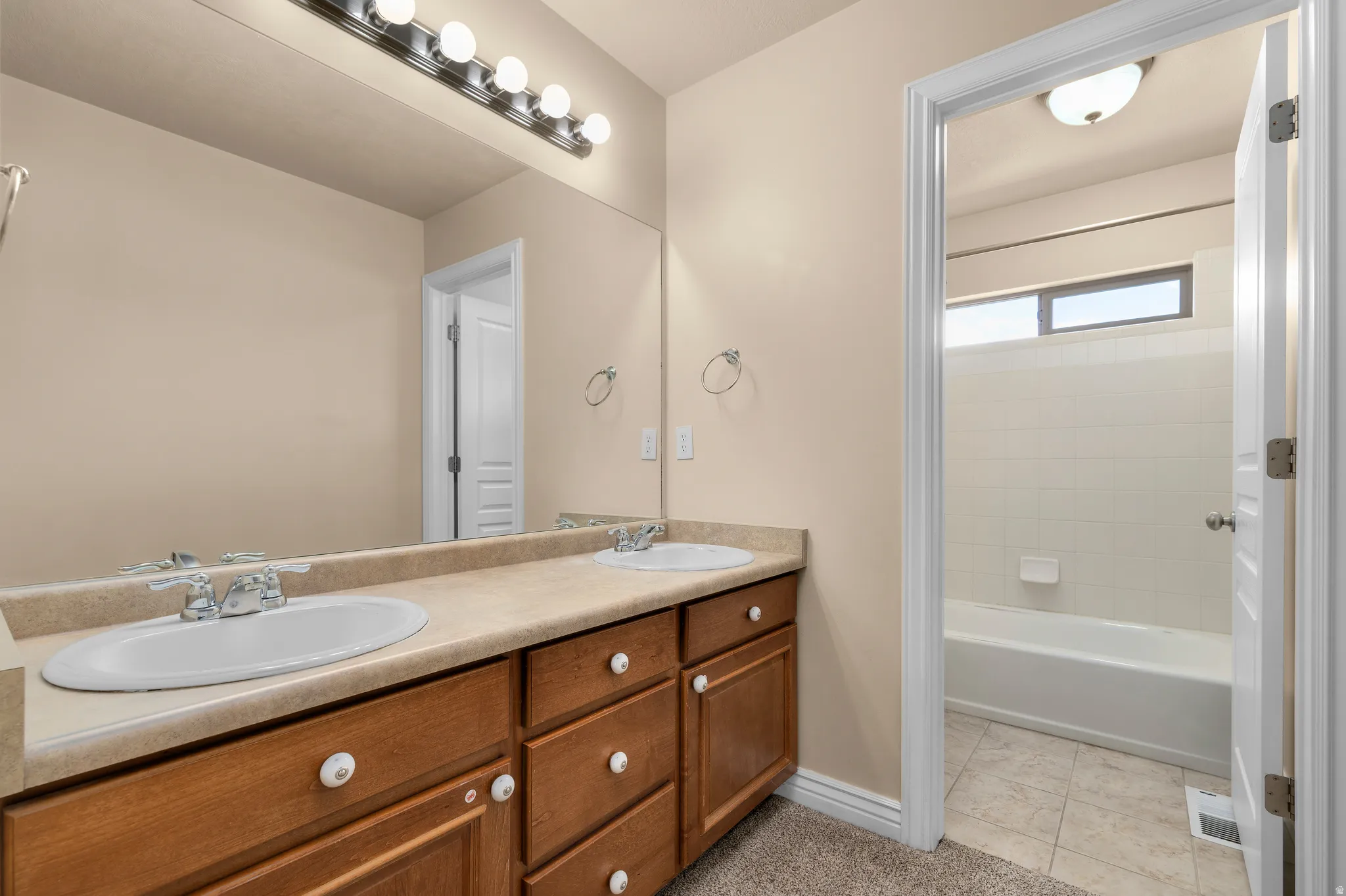 Double vanity with wood-finish cabinetry and a neutral countertop