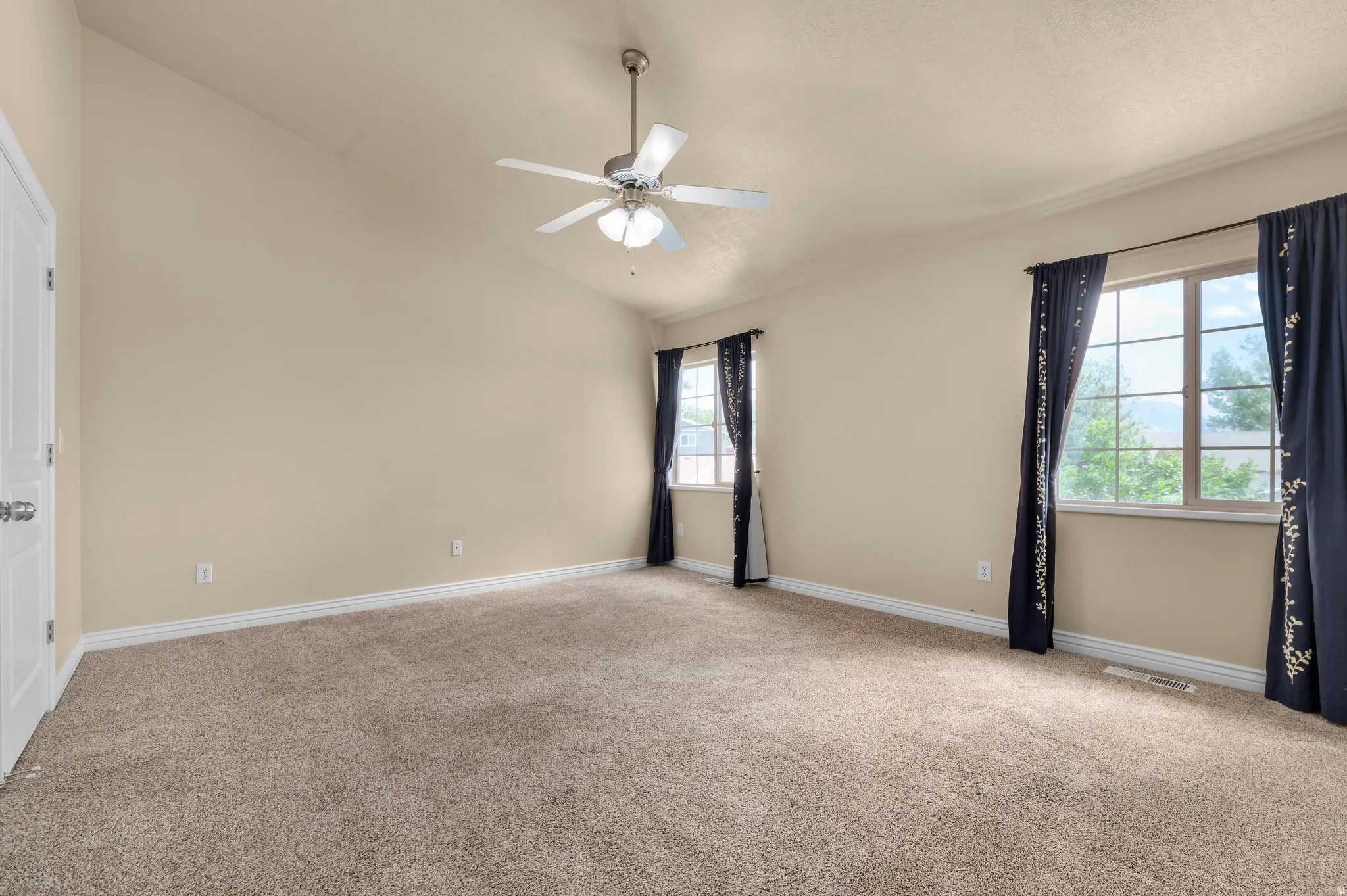 Spacious room featuring vaulted ceilings, neutral-toned walls, and plush carpeting