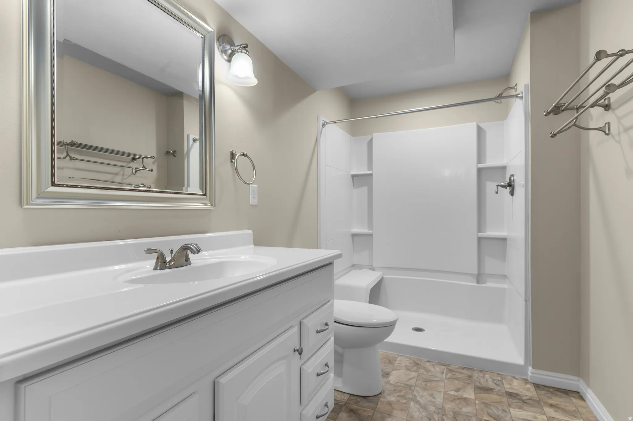 Bathroom featuring a white vanity with integrated sink, coordinating white cabinetry, and a framed mirror