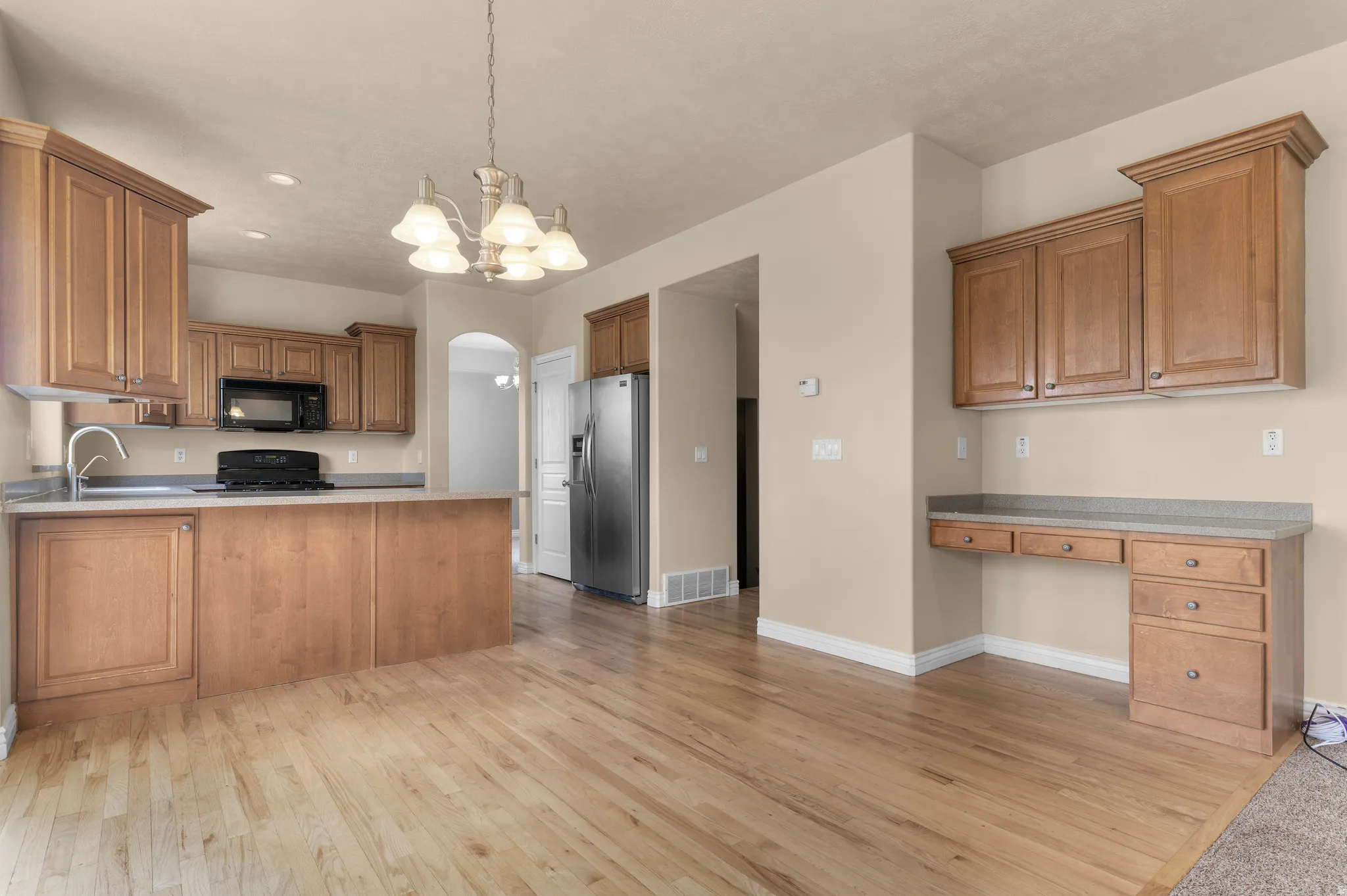 Open-concept kitchen and dining area featuring wood-finish flooring, wood cabinetry, and light-toned countertops