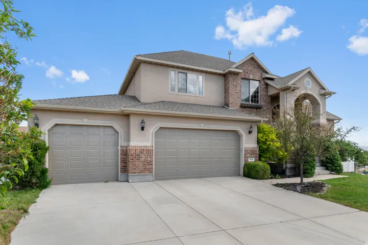 Stucco exterior with brick accents and a multi-car concrete driveway
