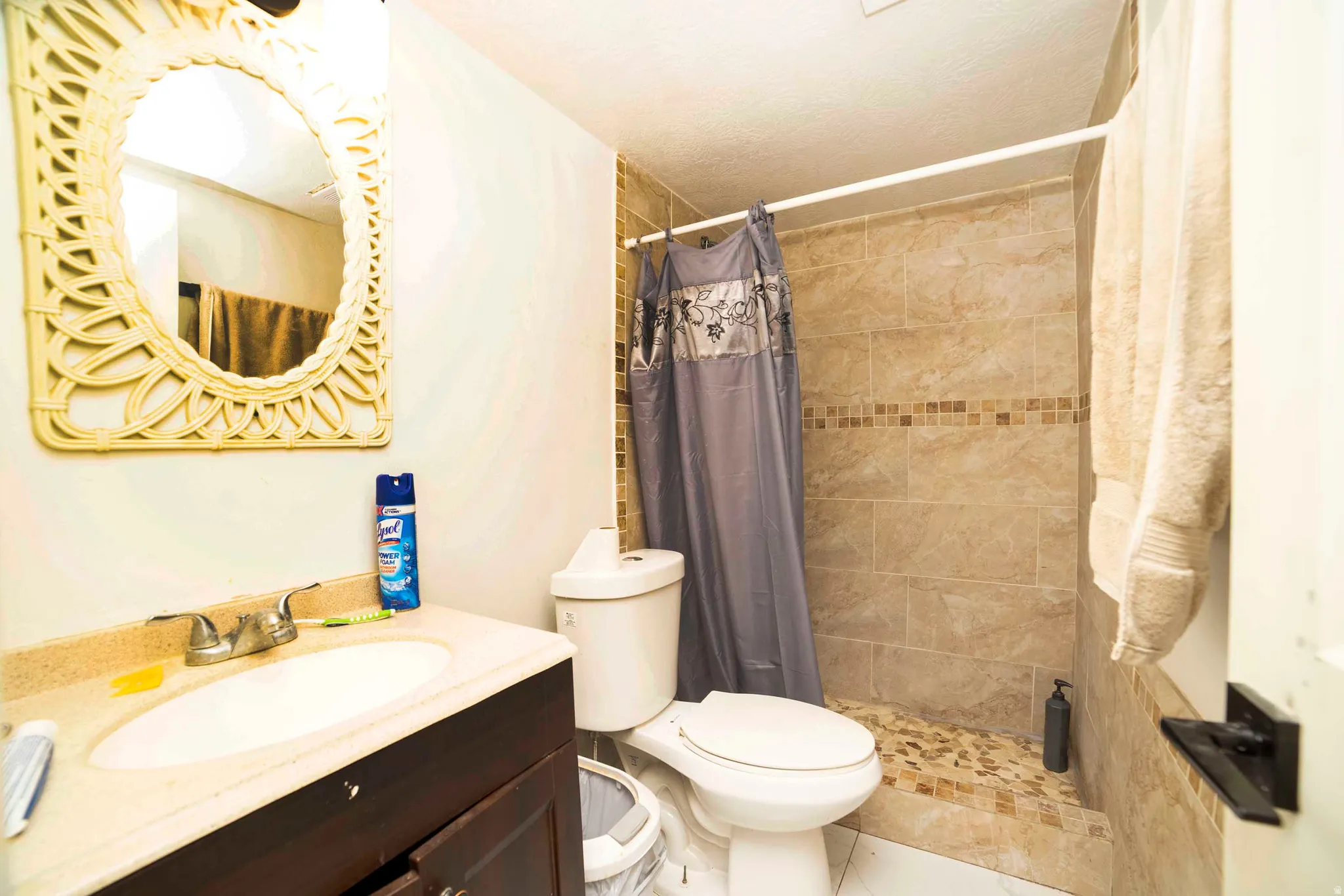 Spacious shower stall with stone tile surround and mosaic accent band