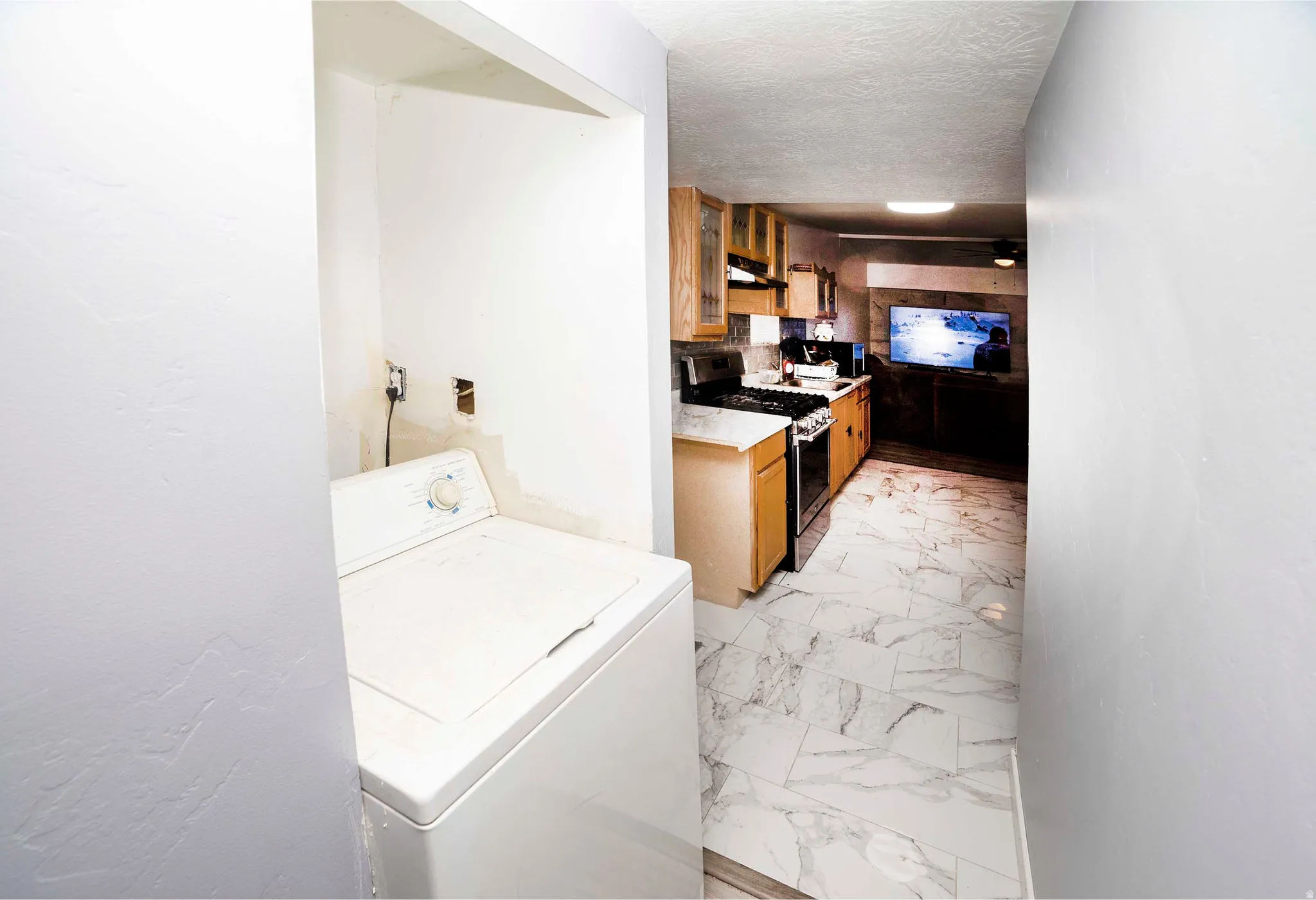 Kitchen with wood-finish cabinetry, black appliances, and marble-look tile flooring