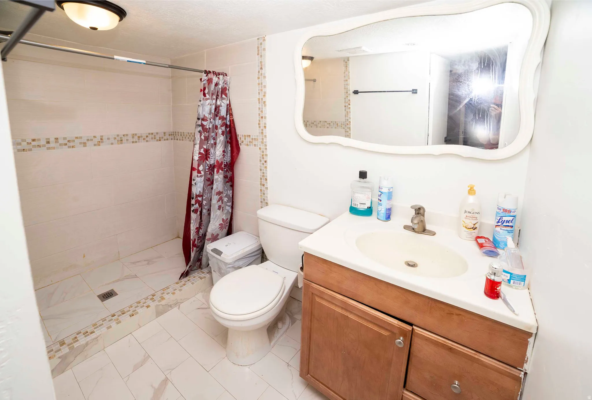 Bathroom featuring a tiled shower with mosaic accent, vanity with a rectangular basin, and wood-finish cabinetry