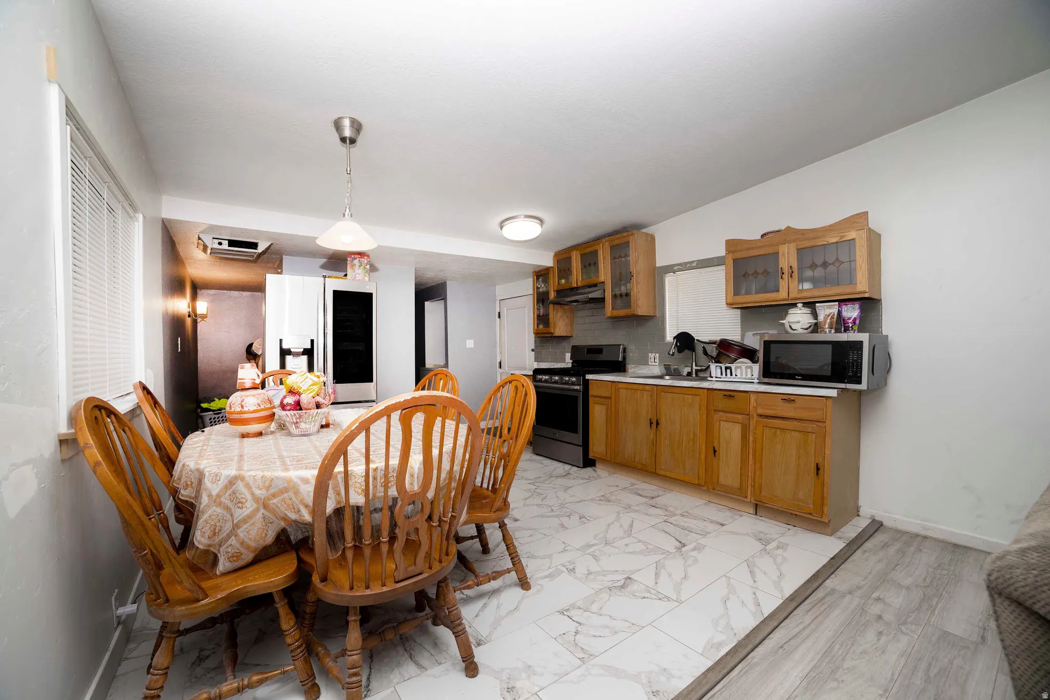 Open-concept kitchen and dining area featuring wood-finish cabinetry, a stainless steel refrigerator, and a gas range