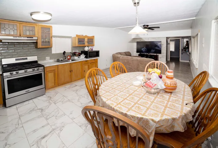 Kitchen featuring light wood cabinetry, stainless steel range, white countertops, gray subway tile backsplash, and marble-look floor tiling