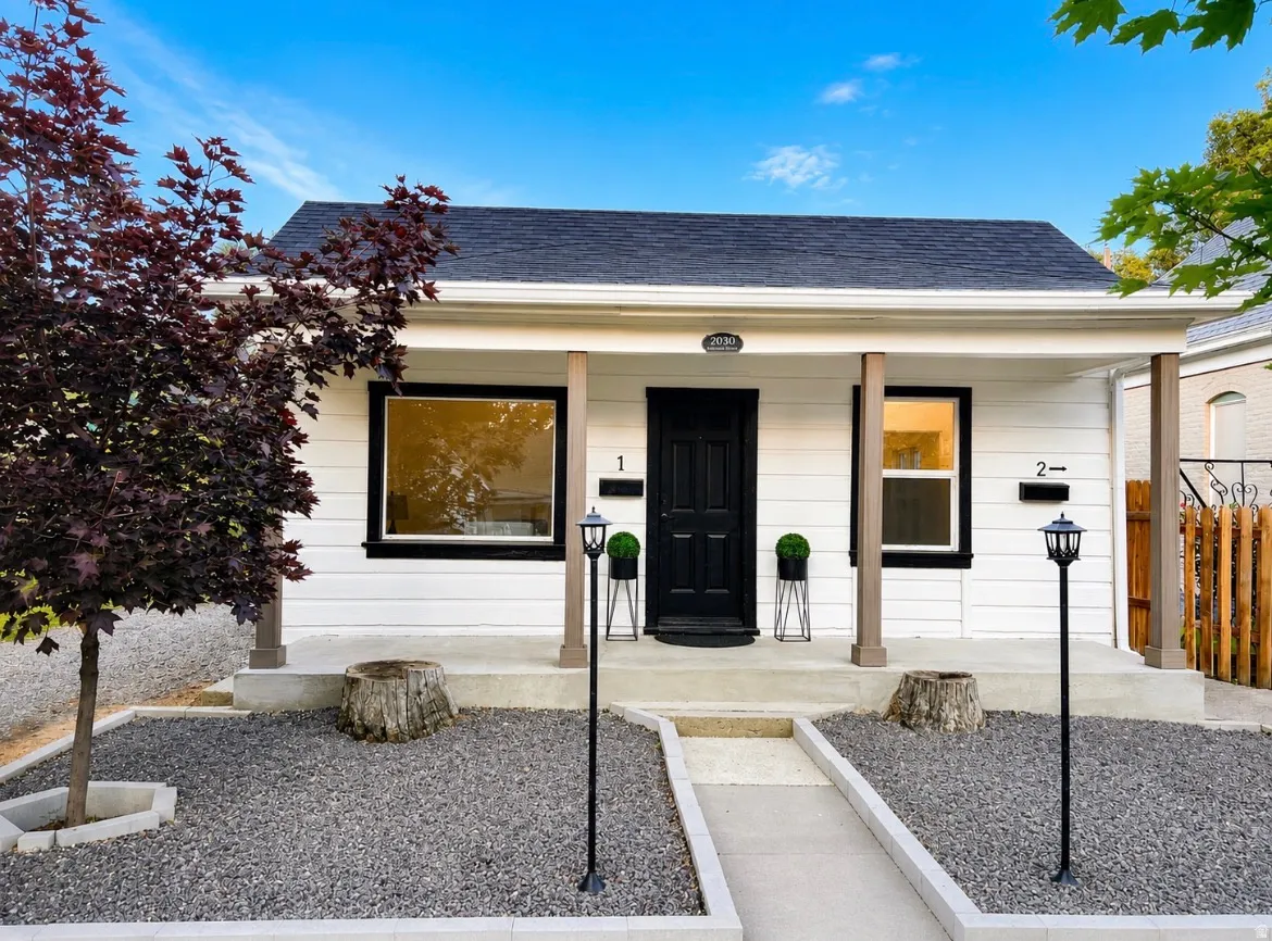 White siding exterior with a dark shingle roof and a covered front porch supported by brown columns