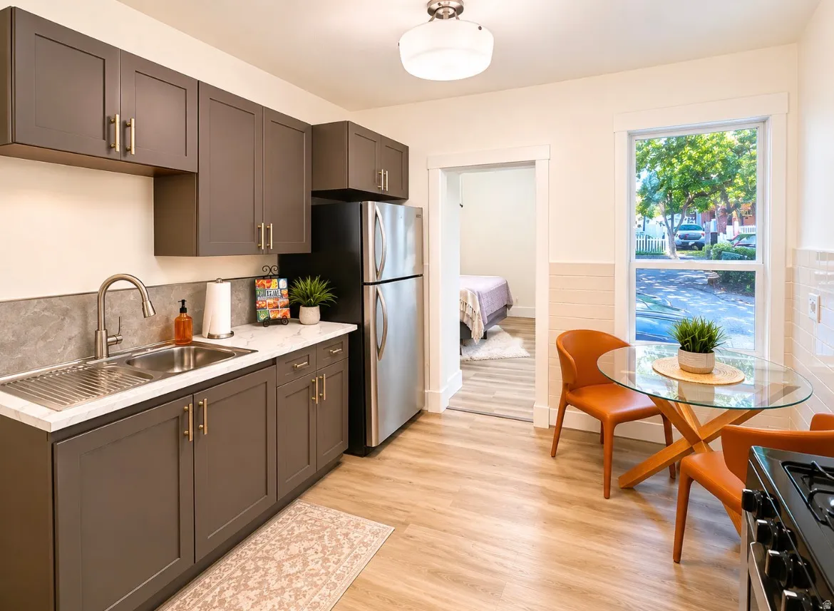 Unit 1 kitchen. Modern kitchen featuring grey shaker cabinetry, brushed gold hardware, stainless steel appliances, light-toned wood-finish flooring, and a large window with white trim