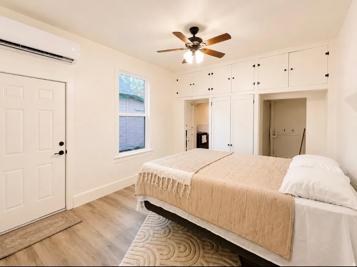 Unit 1 bedroom. Room featuring wood-finish flooring, built-in cabinetry, a ceiling fan with integrated lighting, and a single window
